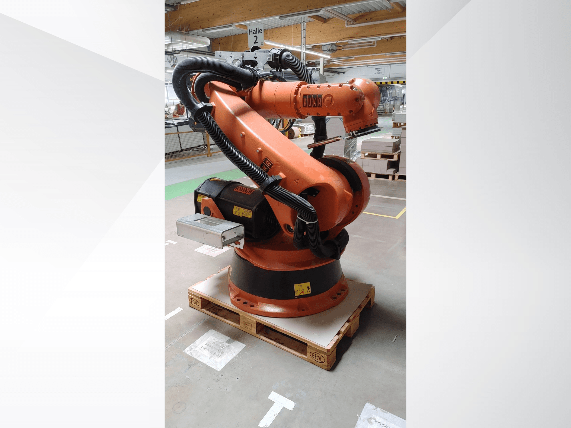 KUKA KR140-3 COMP robotarm i orange, framifrån på en träpall, med böjd arm och kontrollbox.