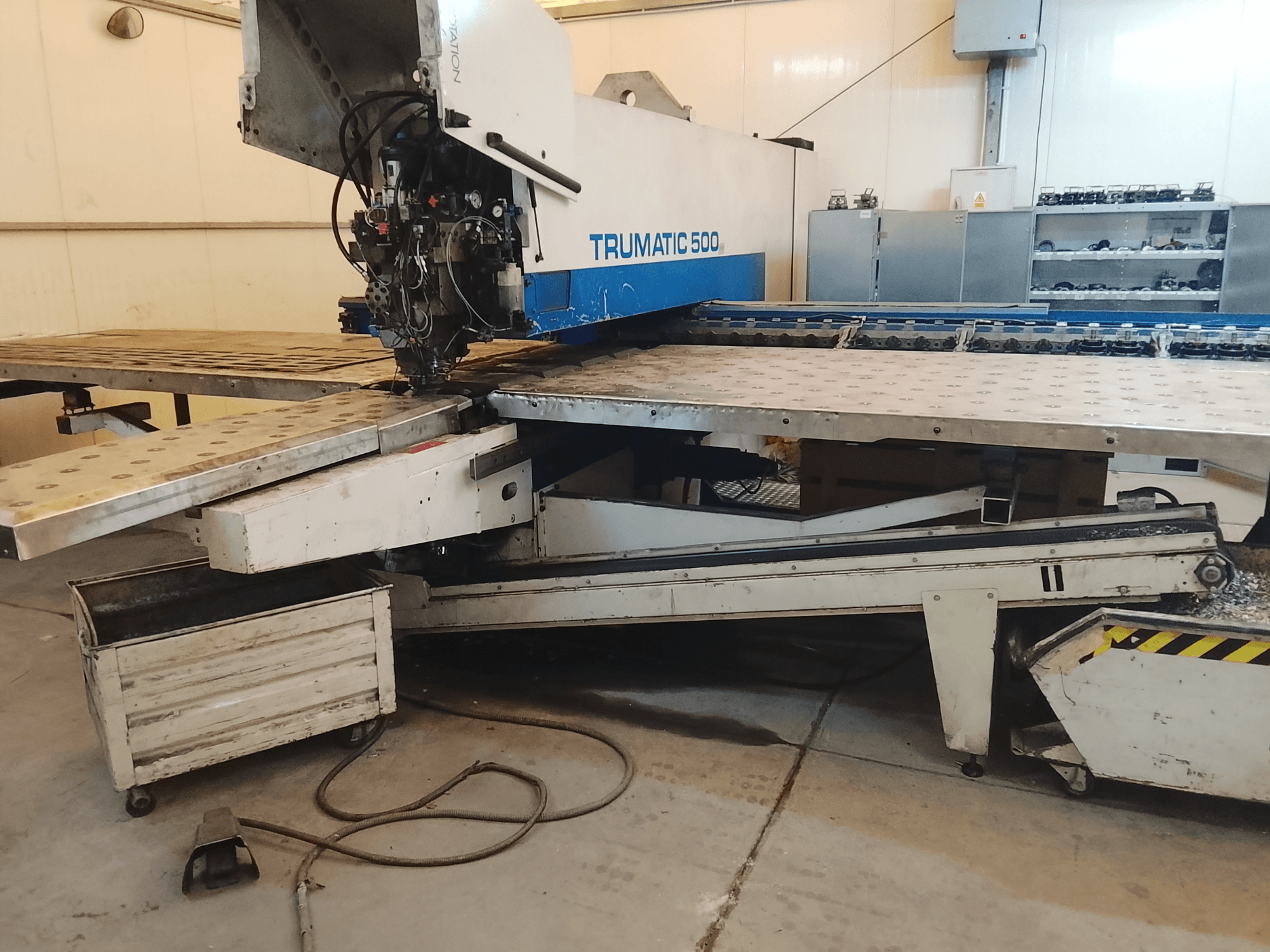 TRUMATIC 500 CNC-maskin i en verkstad, sidovy som visar skärhuvud och arbetsbord i metall med förborrade hål.