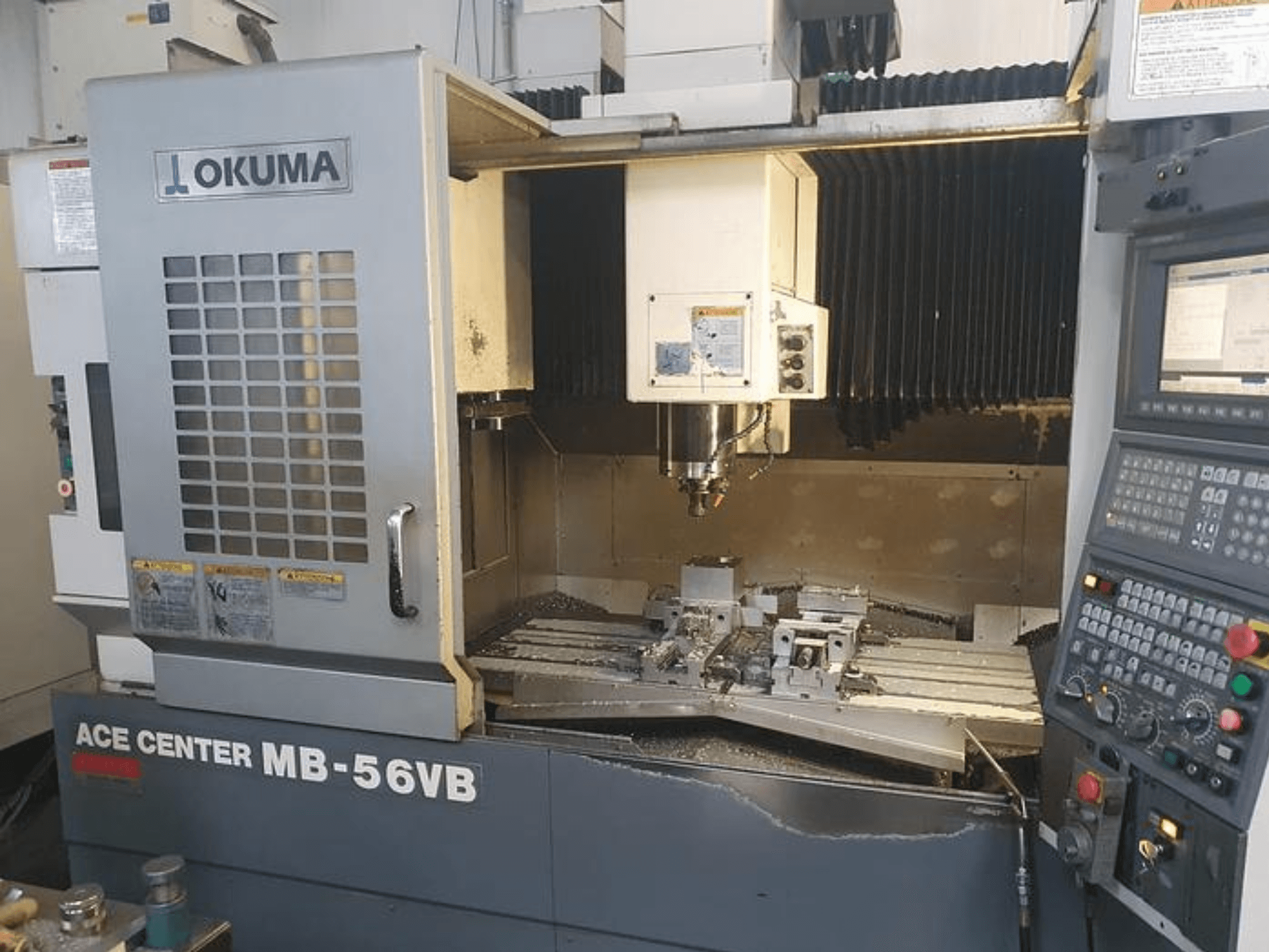 Okuma ACE CENTER MB-56VB CNC-fräsmaskin i frontvy, som visar kontrollpanelen och bearbetningsområdet.