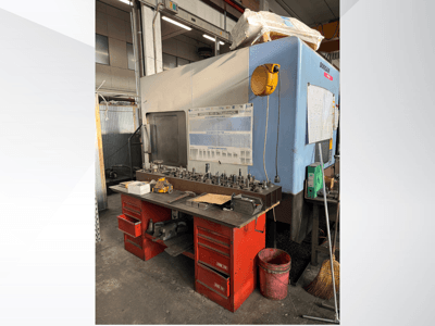 Doosan bearbetningscenter med röd arbetsbänk och förvaring, där verktyg och utrustning visas, sett framifrån.