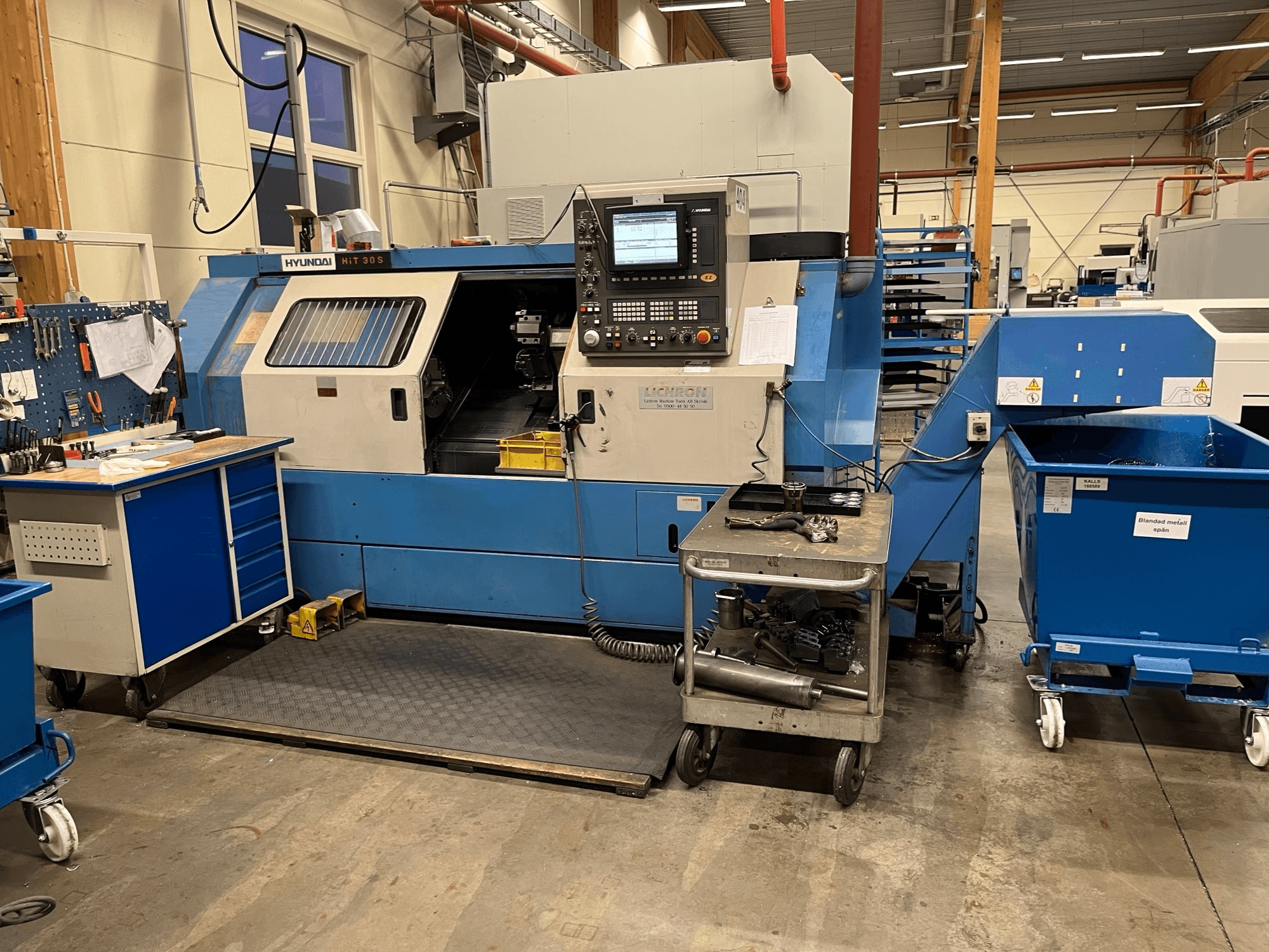 Hyundai HIT 30S horisontell svarv, framifrån, med kontrollpanel och verktyg på en närliggande vagn i en verkstadsmiljö.