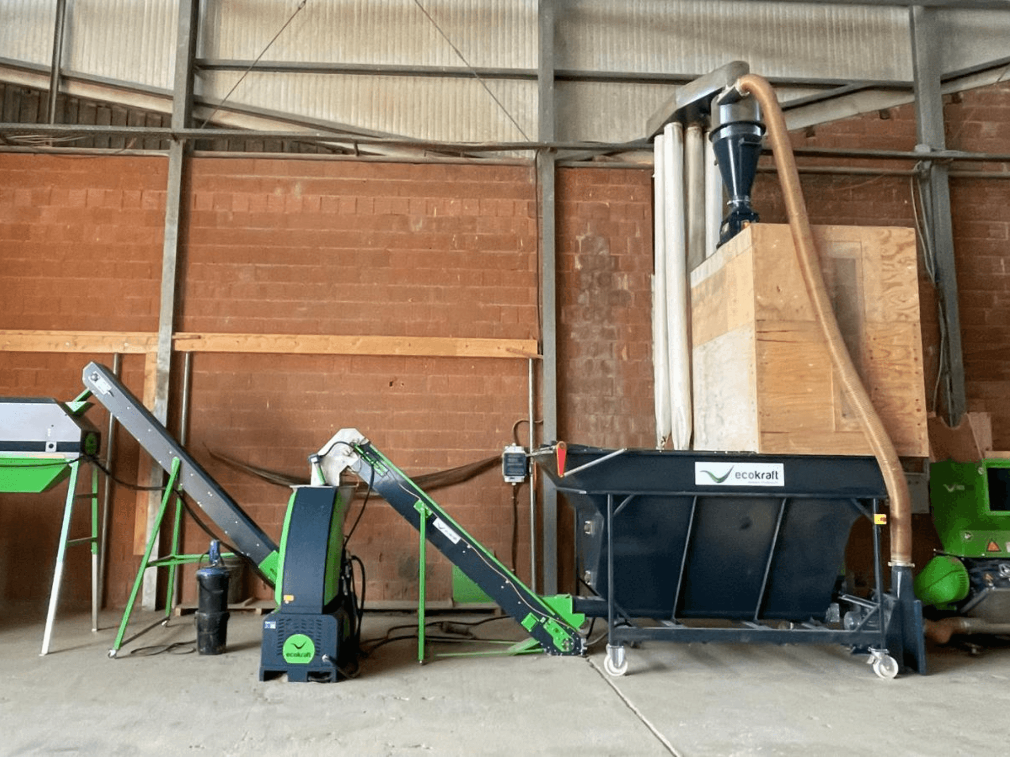 Verktygsmaskinen ECOKRAFT LP 22 i ett lager, utrustad med transportband och dammuppsamlingssystem. Sidovy som visar de funktionella komponenterna.
