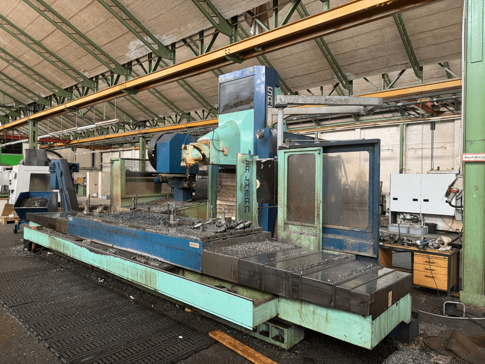 Salvador fräsmaskin i fabriksmiljö, framifrån, med blå och grön färgskala, med metallspån på bädden.