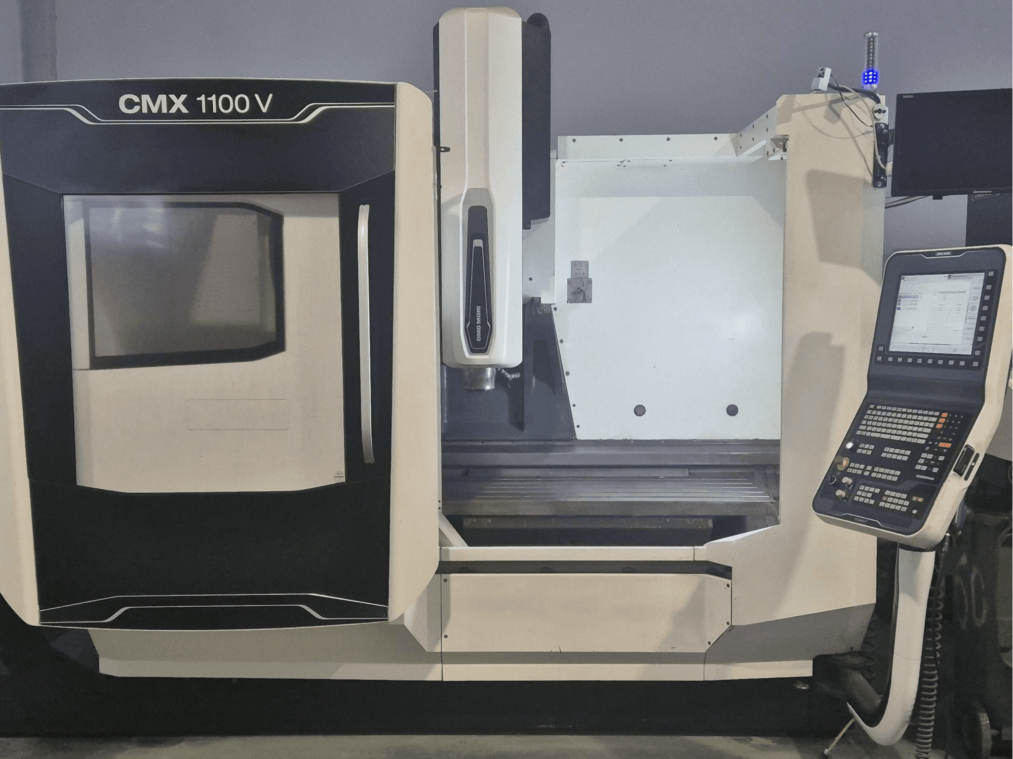 DMG MORI CMX 1100 V vertikalt bearbetningscenter, framifrån med kontrollpanelen och maskinbädden i förgrunden.