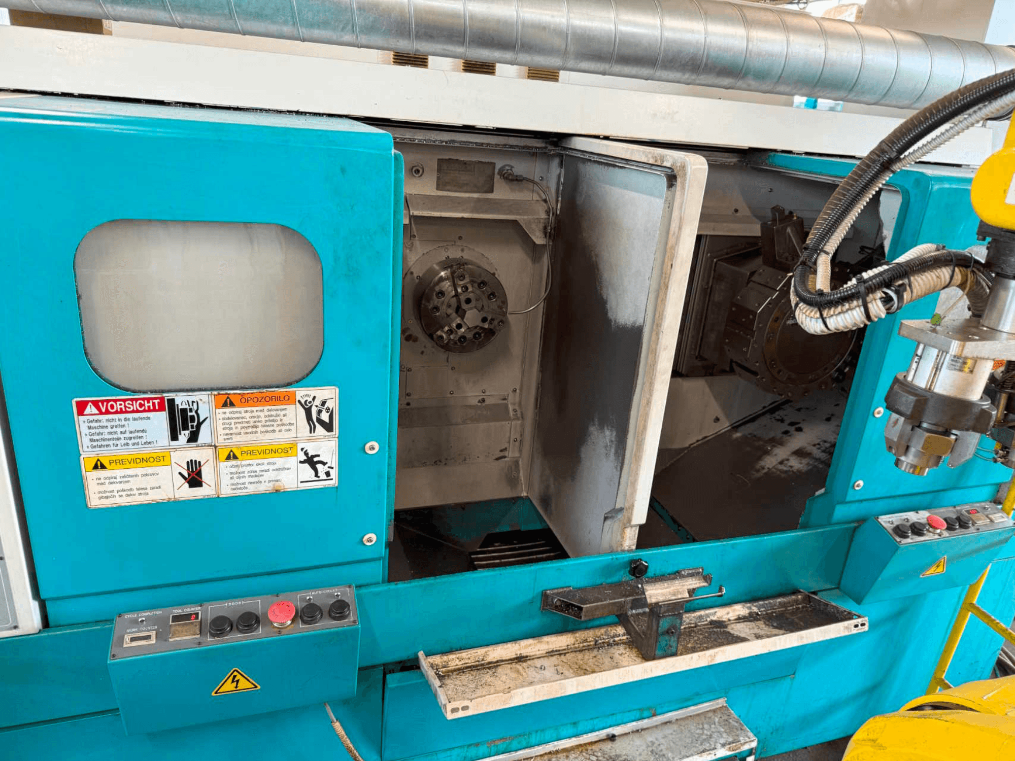 DOOSAN H310T horisontell svarv, framifrån med kontrollpanel och spindelområde med säkerhetsvarningar.