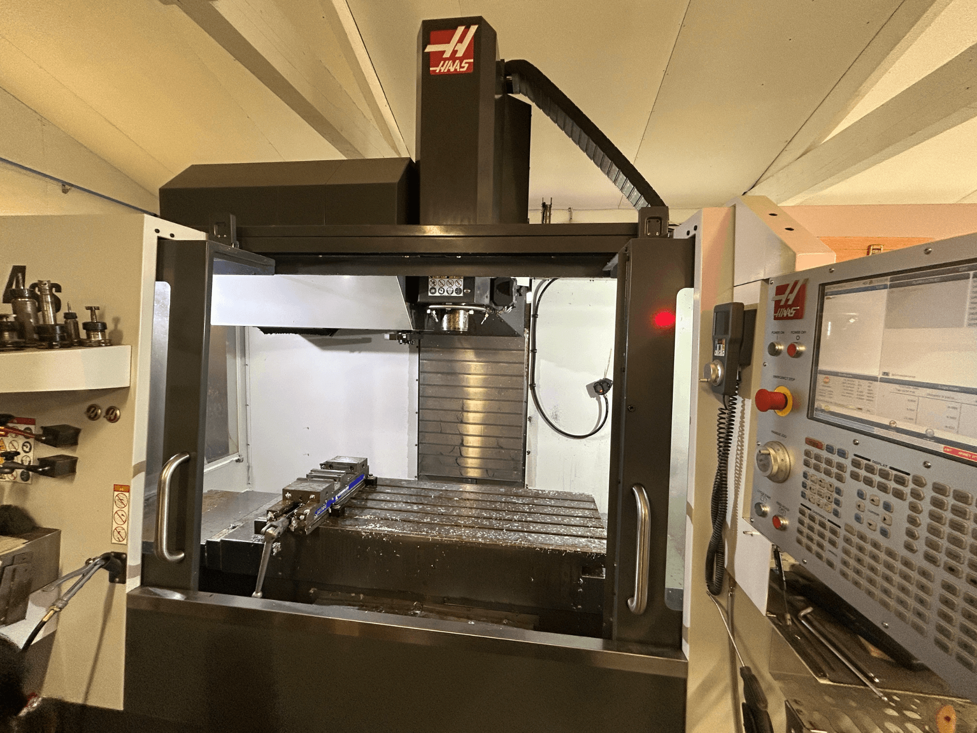 HAAS VF-4SS vertikal fleroperationsmaskin, framifrån, med kontrollpanel, verktygshållare och arbetsområde med metallspån.