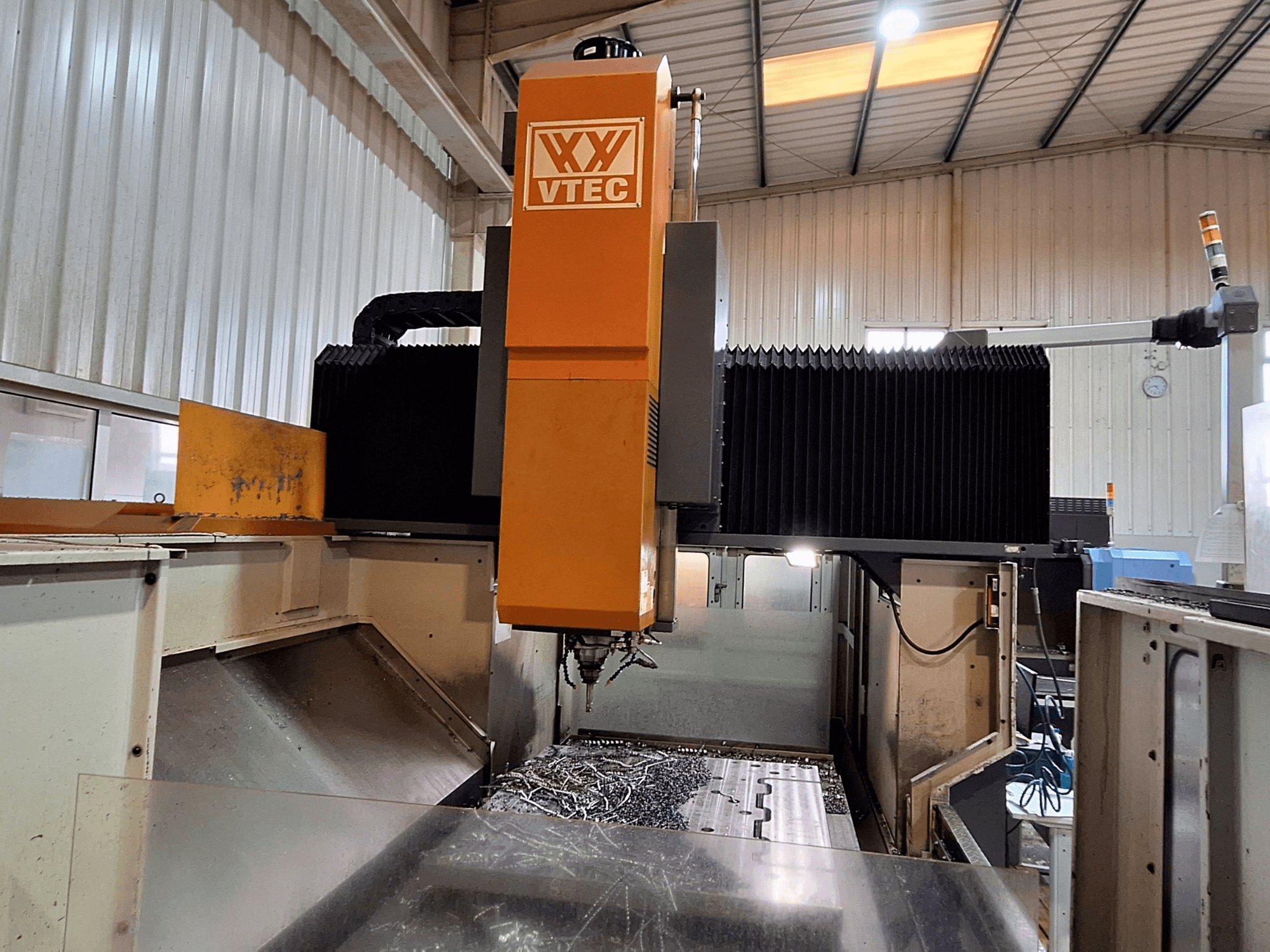 Portalfräsmaskin från PORTIC, modell VTEC, visad framifrån med skärverktyg och metallspån synliga.