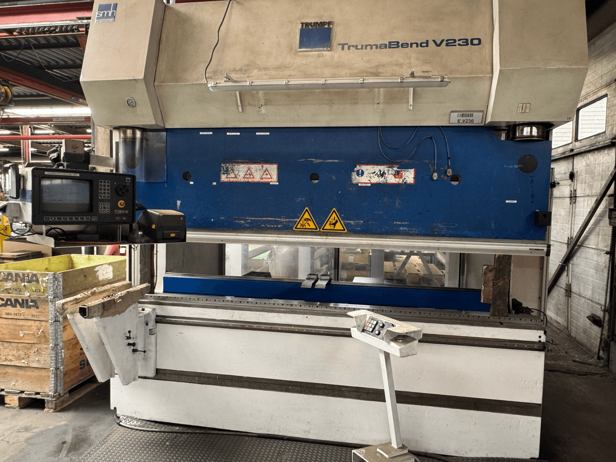 TRUMPF TrumaBend V230 kantpress, vy framifrån med kontrollpanel, varningsetiketter och en stödarm för arbetsstycket synliga.
