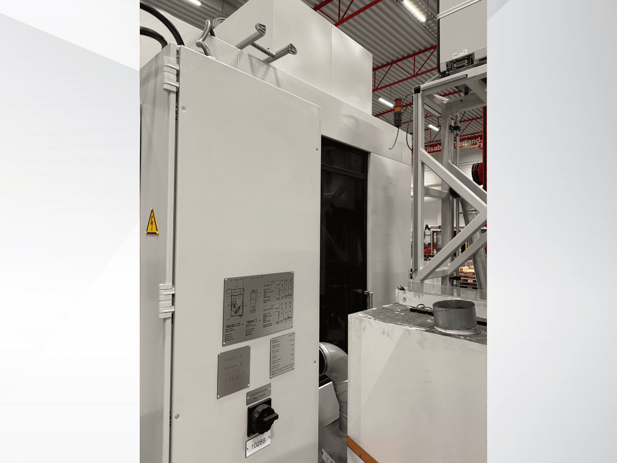 Sidovy av en vit industrimaskin med kontrollpanel och varningsetikett, del av ett automatiserat system.