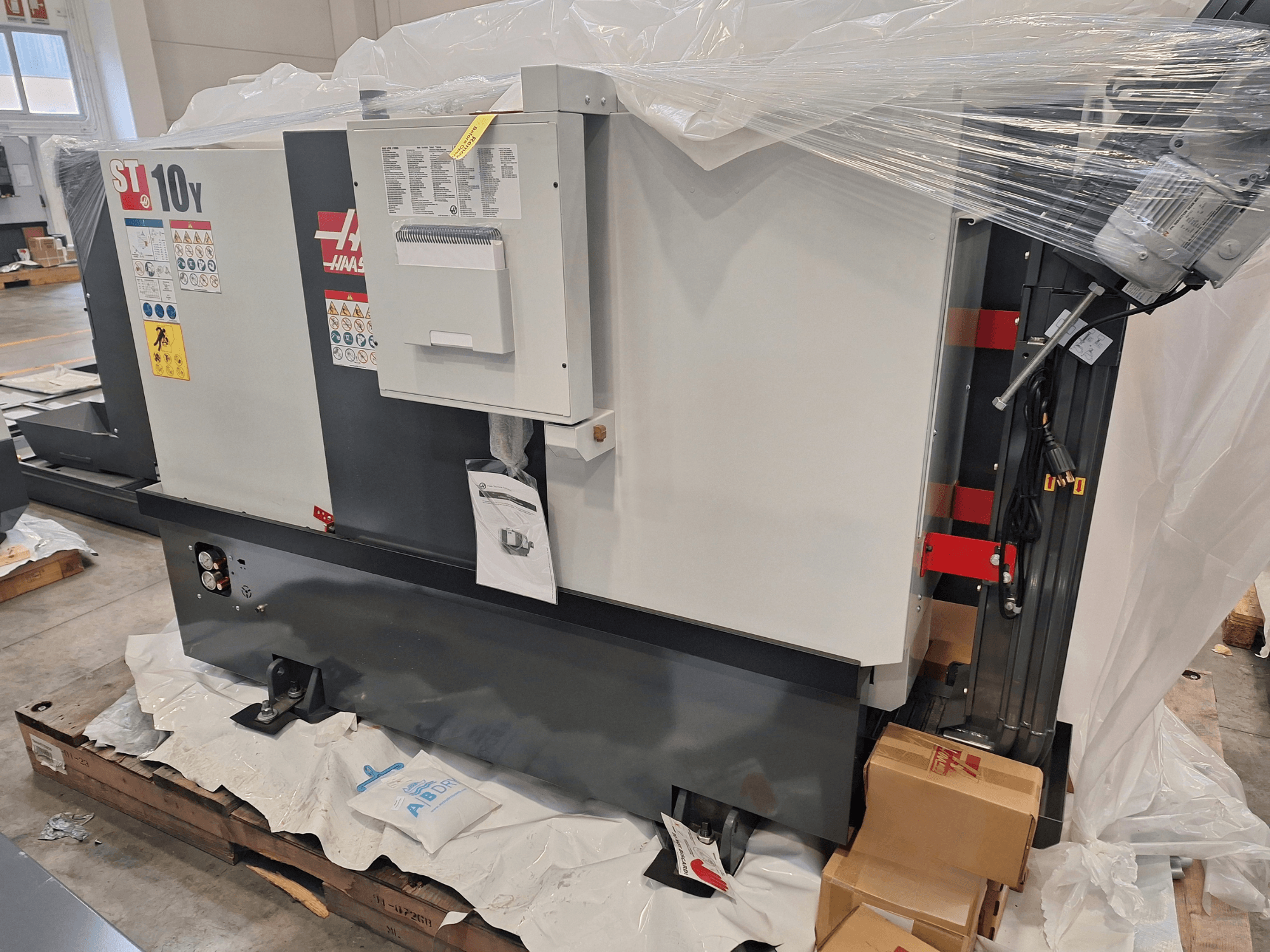 HAAS ST-10Y EU horisontell svarv, sidovy, inplastad, med kontrollpanel och varningsetiketter synliga.