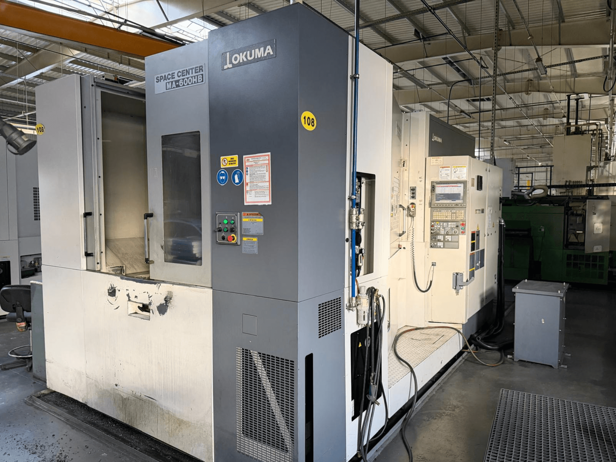 Okuma MA-600 HB horisontell fleroperationsmaskin, framifrån, visar kontrollpanelen och skärområdet med synliga slitagemärken.