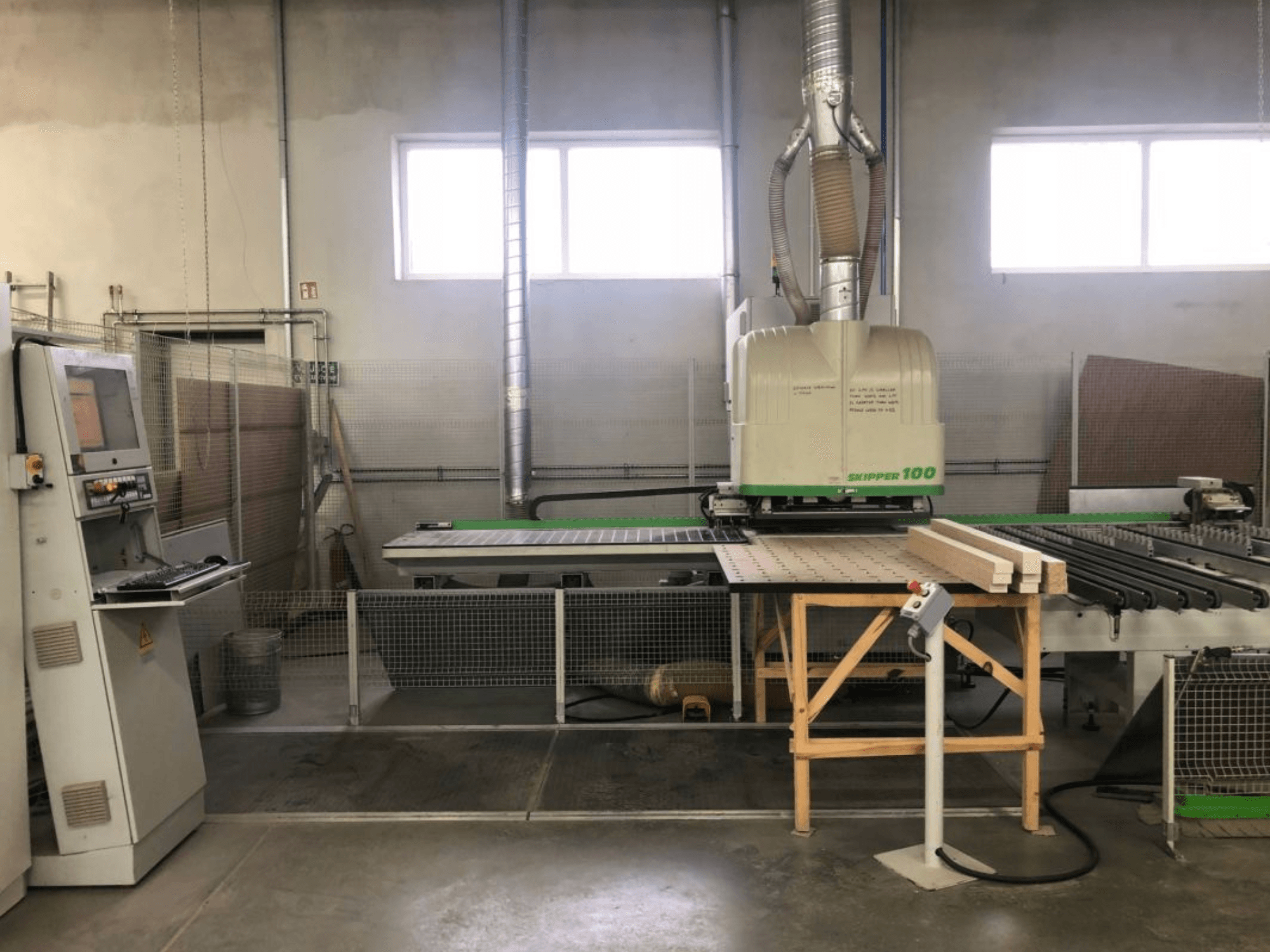 BIESSE SKIPPER 100 CNC-bearbetningscenter i en verkstad; framifrån sett syns maskinen med kontrollpanelen och träet på arbetsbordet.