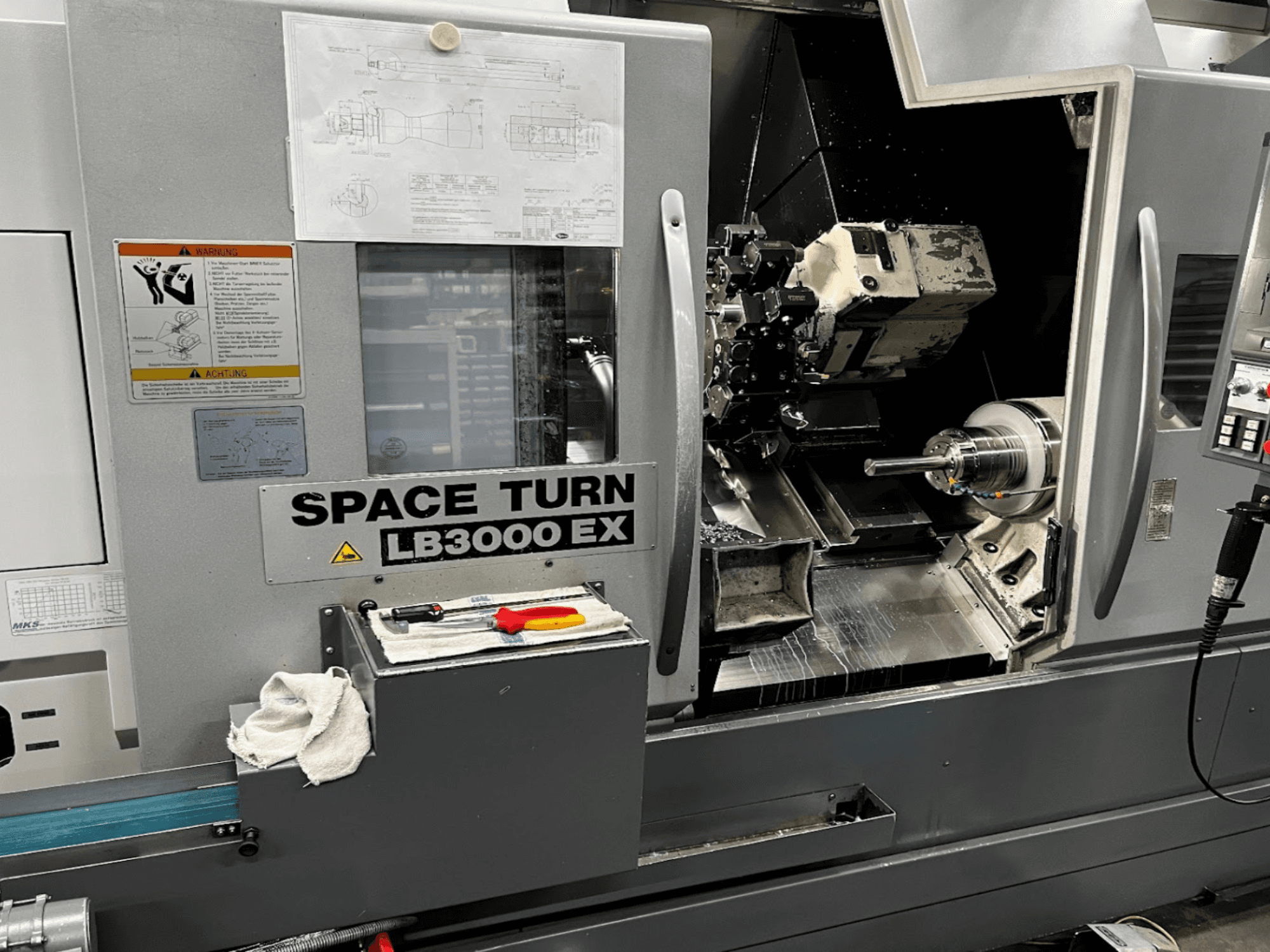 Okuma LB3000EX MYW horisontell svarv, framifrån med kontrollpanel, verktyg och detaljer i arbetsutrymmet synliga.