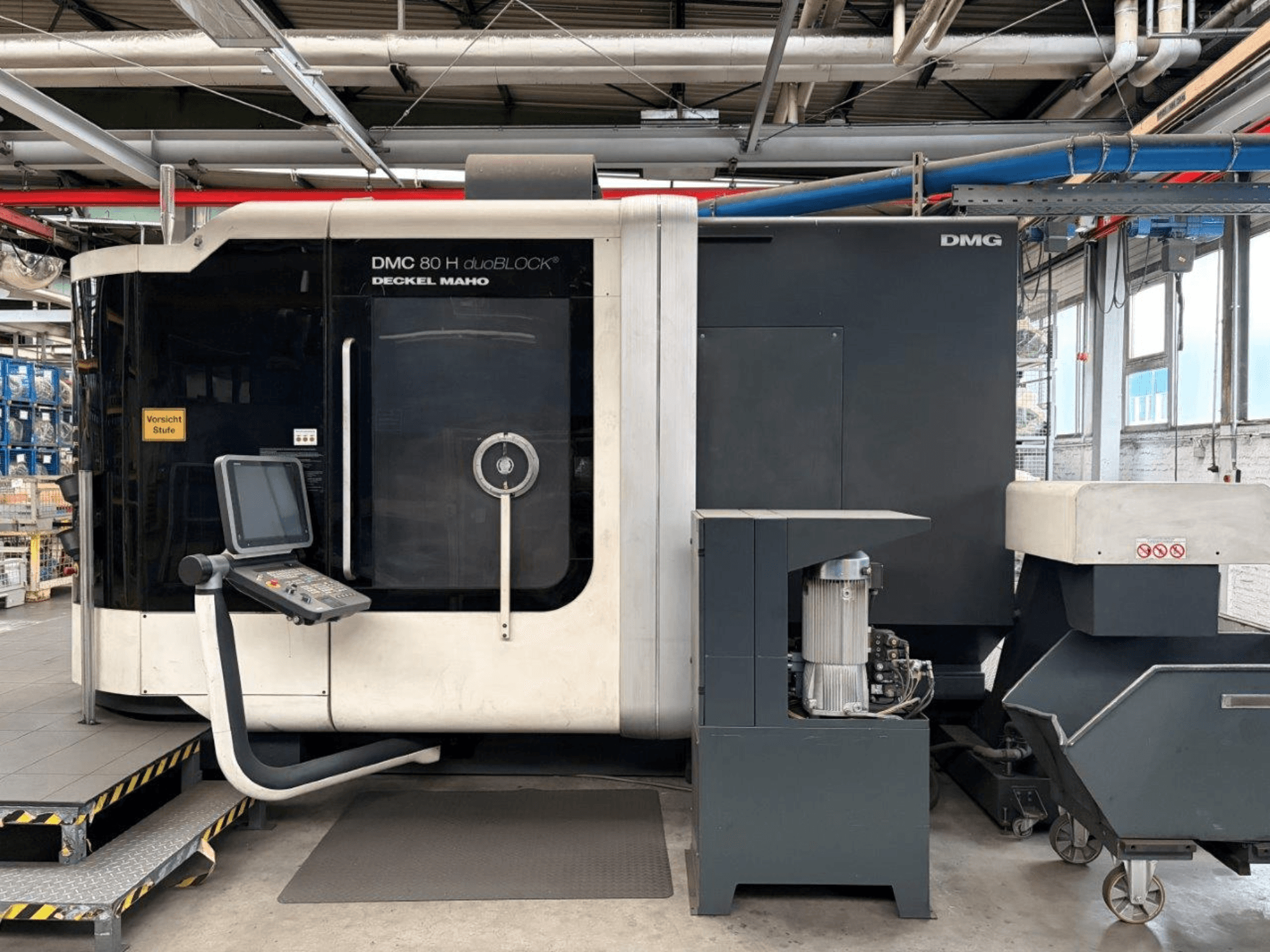 Horisontell vy av DECKEL MAHO DMC 80 H duoBLOCK bearbetningscenter, med kontrollpanel och maskindetaljer.