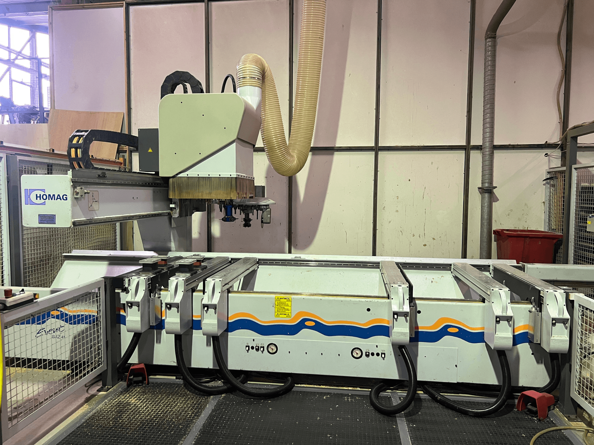 HOMAG BIZ 4 CNC-maskin i verkstad; framifrån med dammutsugningssystem och kontrollpanel med kablar.