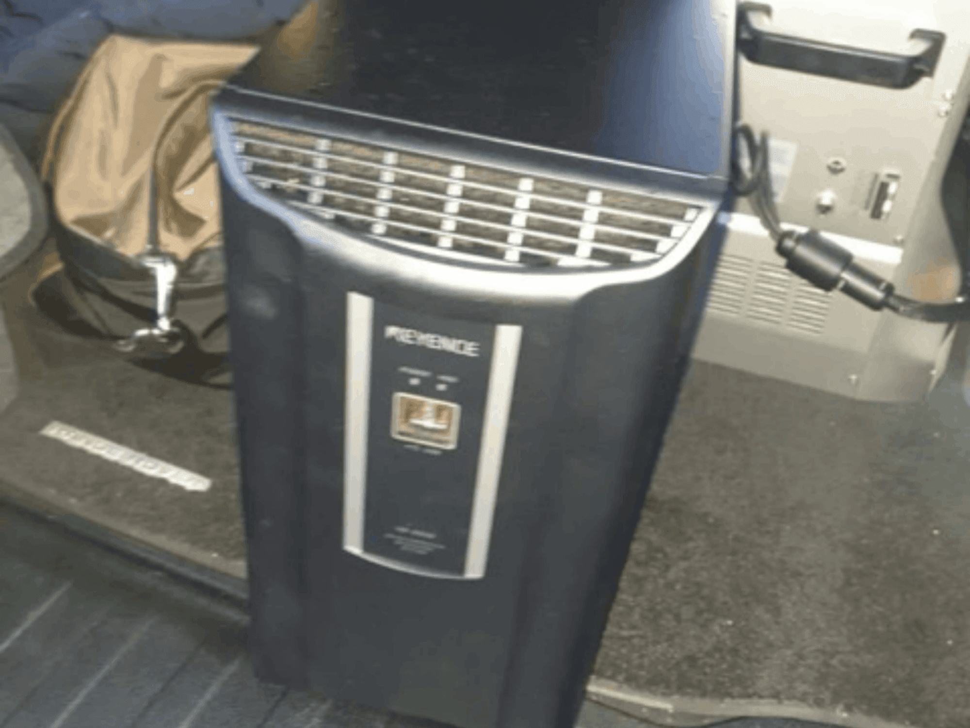 KEYENCE IM-8030 automationssystem framifrån, med kontrollpanel och ventilationsöppningar, mot en bakgrund av en fordonsinteriör.