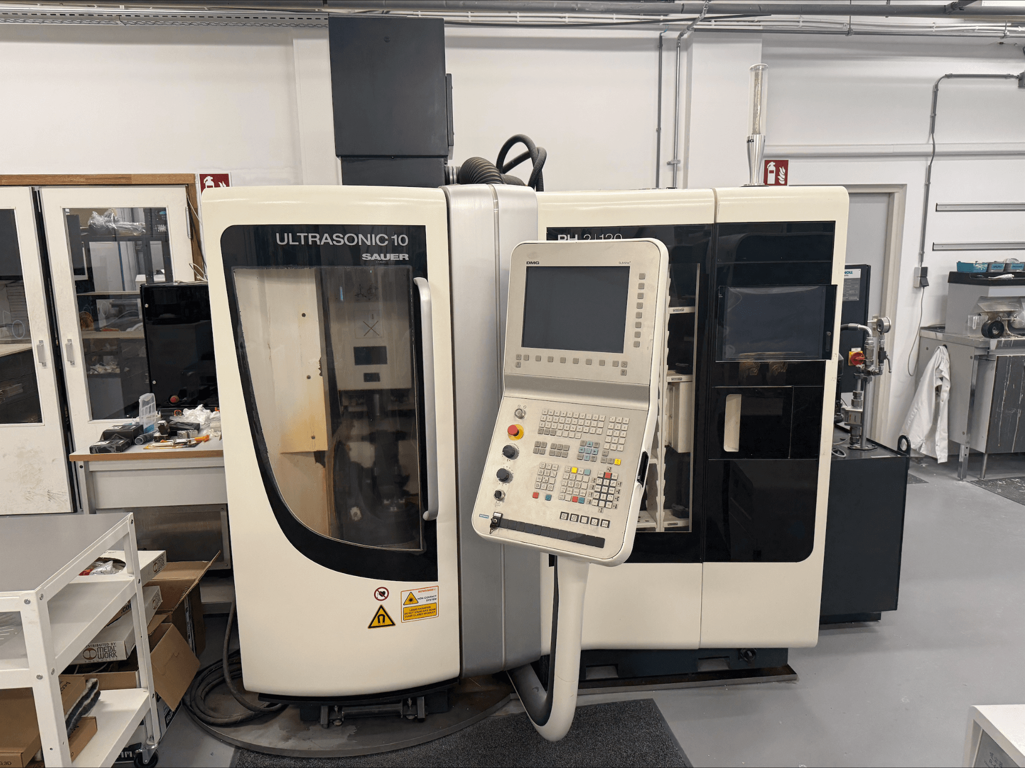 DMG Sauer Ultrasonic 10 + PH 2 | 120 vertikal bearbetningscenter, framifrån, med kontrollpanel och stort visningsfönster.