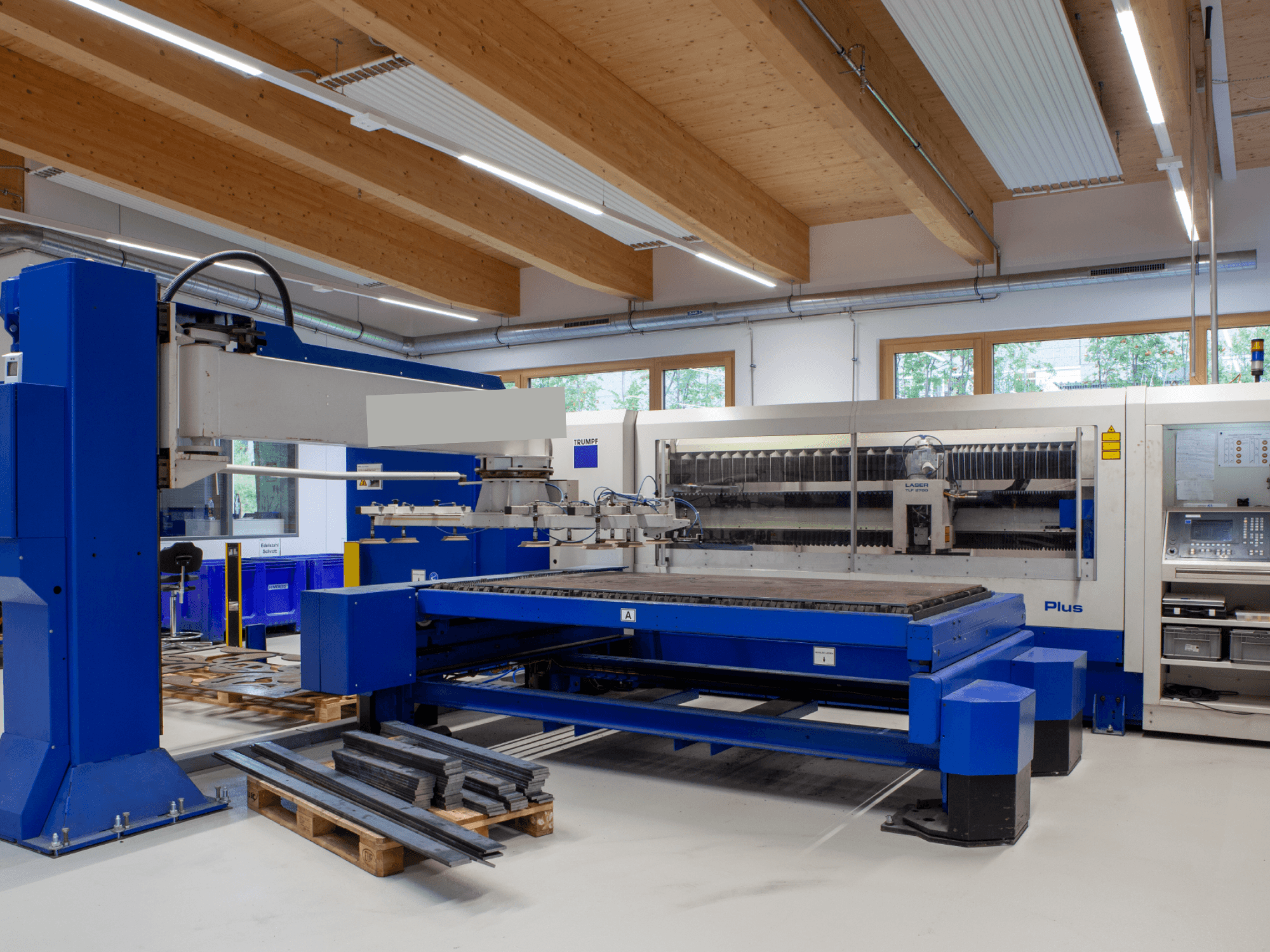 En TRUMPF TRUMATIC L 2530 Plus CO₂-laserskärmaskin i en verkstad, med ett stort skärbord och industriell design.