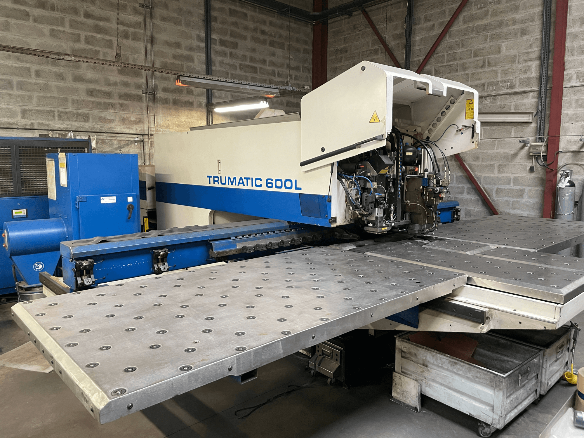 CO2-laserskärmaskin TRUMPF TRUMATIC TC 600L, framifrån med metallskärbord och kontrollpanel synlig.