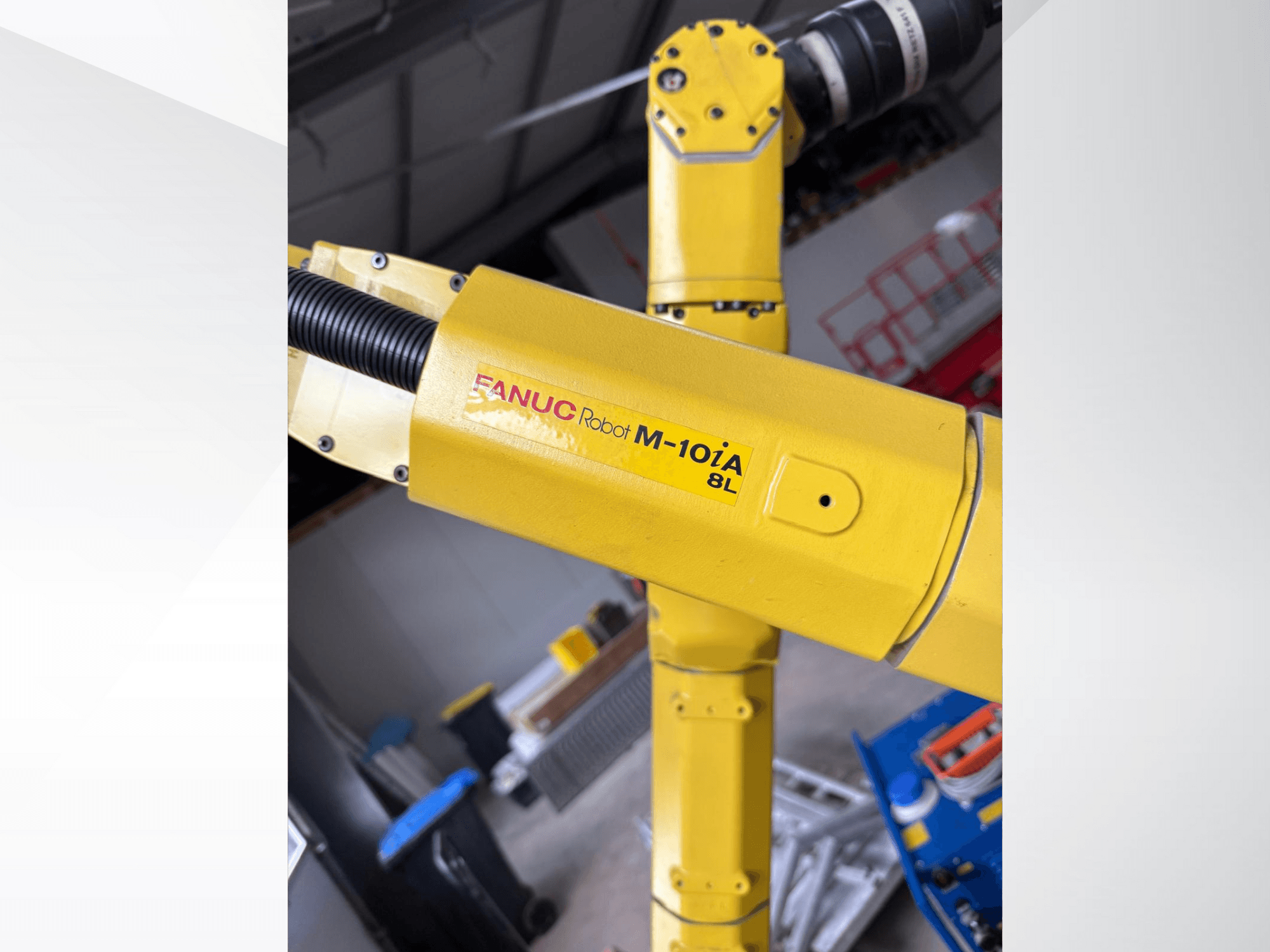 FANUC Robot M-10iA 8L i gult, sedd från sidan, visar upp armled och mekaniska komponenter i en industriell miljö.