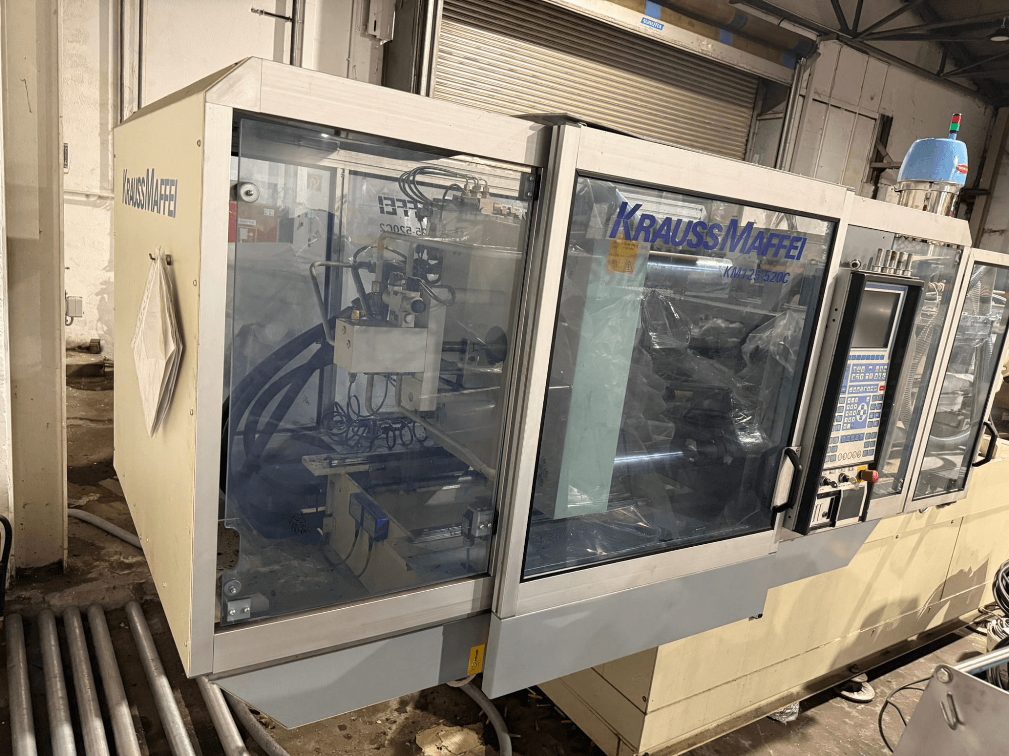 Krauss Maffei KM125-520C2 hydraulisk formsprutningsmaskin, framifrån med kontrollpanel och transparent hölje.
