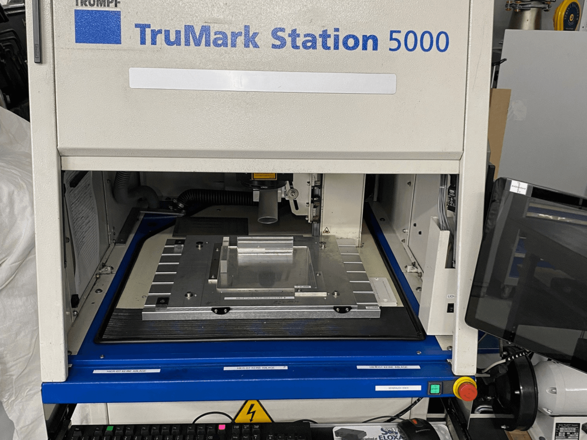 TruMark Station 5000 lasermärkningsmaskin framifrån med arbetsbord, reglage och övervakningsskärm.