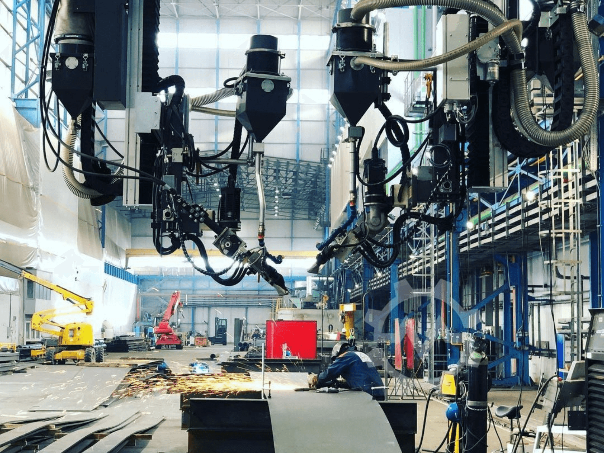 Robotstyrd skärmaskin i industrimiljö med gnistregn, sedd från sidan; har flera tillbehör och slangar.