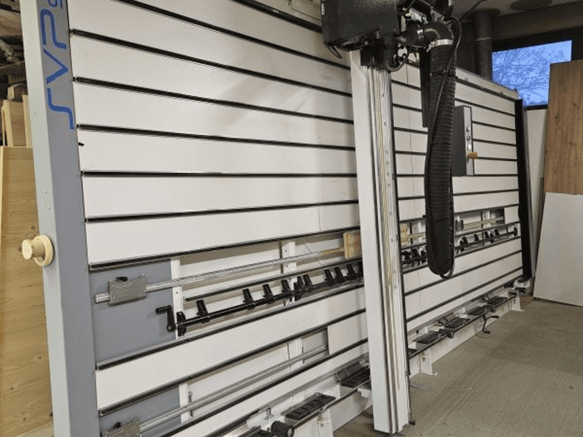 SVP glidande panelsåg i en verkstad, framifrån, med justerbara spår och dammutsugningssystem ovanför huvudet.