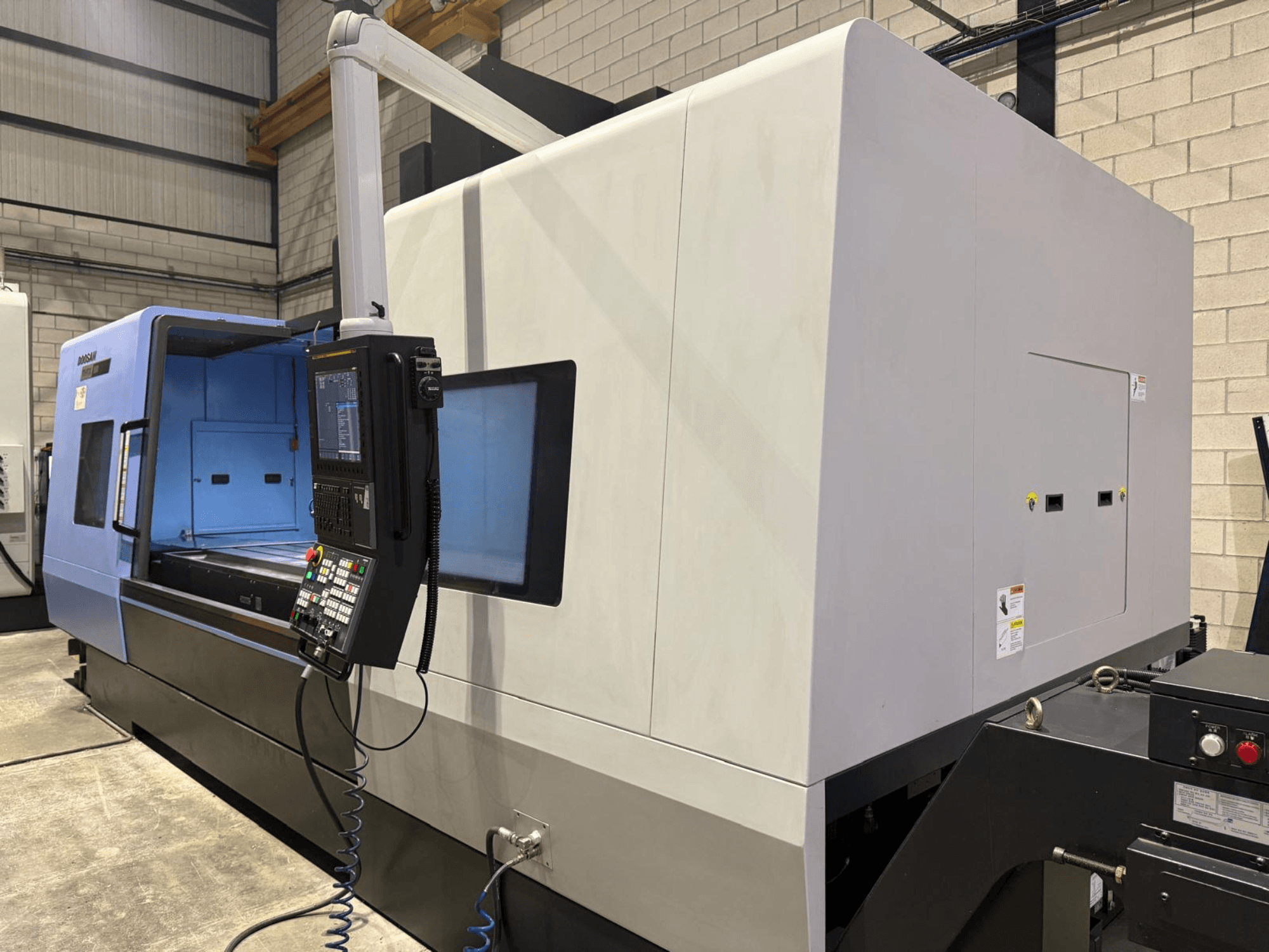Industriell CNC-svarv, blå och grå exteriör, framifrån; har kontrollpanel med knappar och display för exakta operationer.