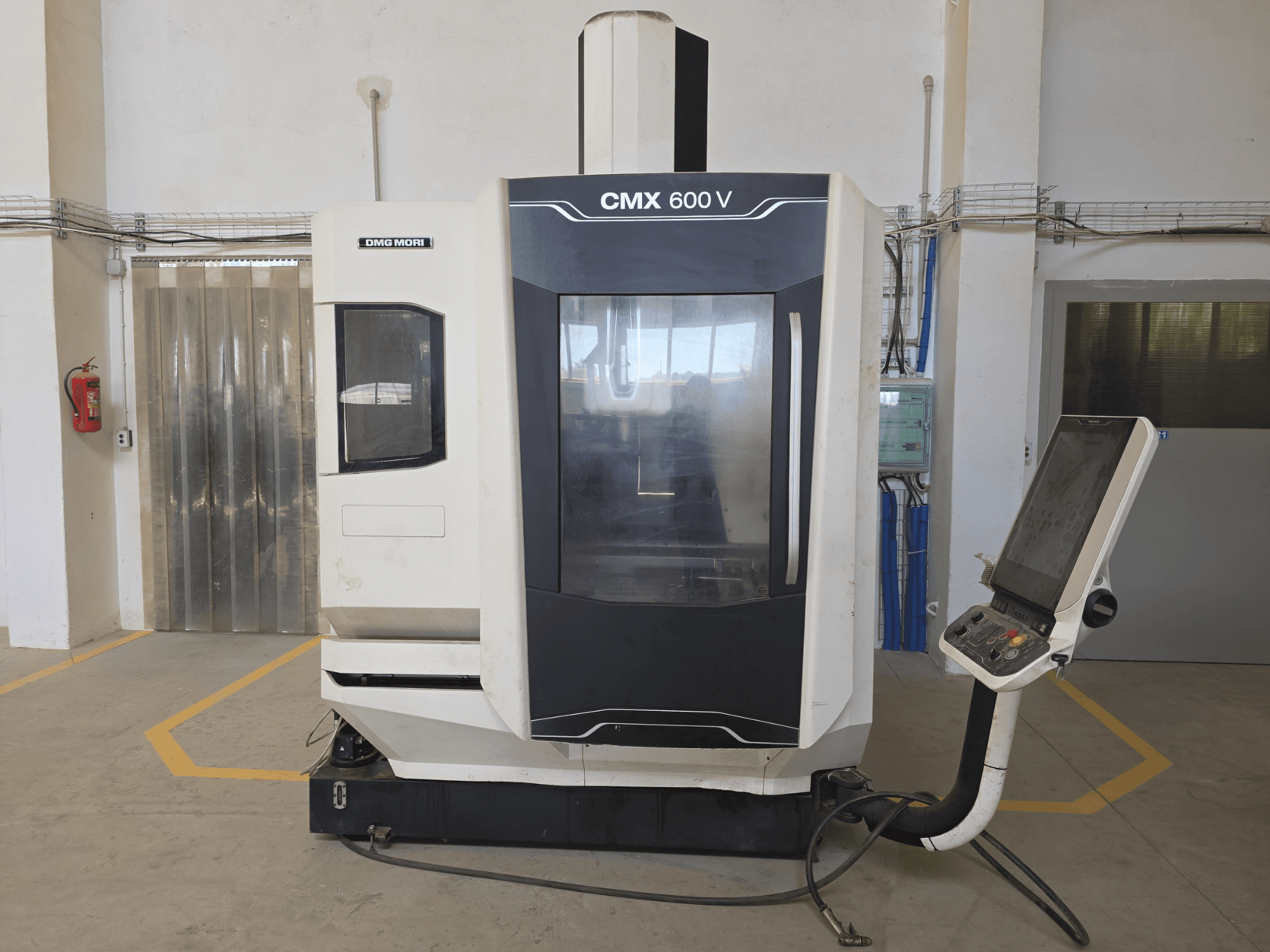 DMG MORI CMX 600 V vertikalt bearbetningscenter, framifrån, med kontrollpanel och stort genomskinligt fönster.