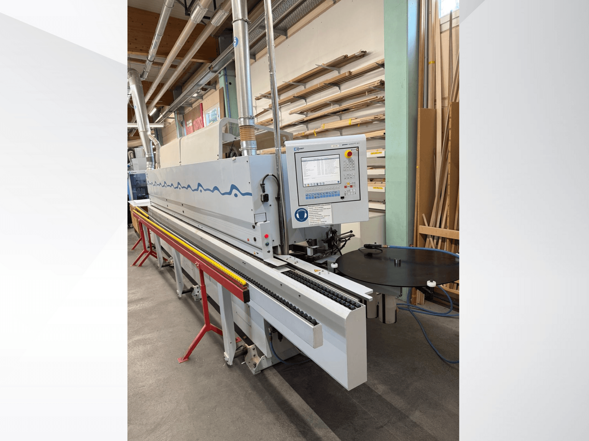 Frontvy av en automatisk kantlistningsmaskin från HolzHer med kontrollpanel, transportörsystem och runt stödbord.