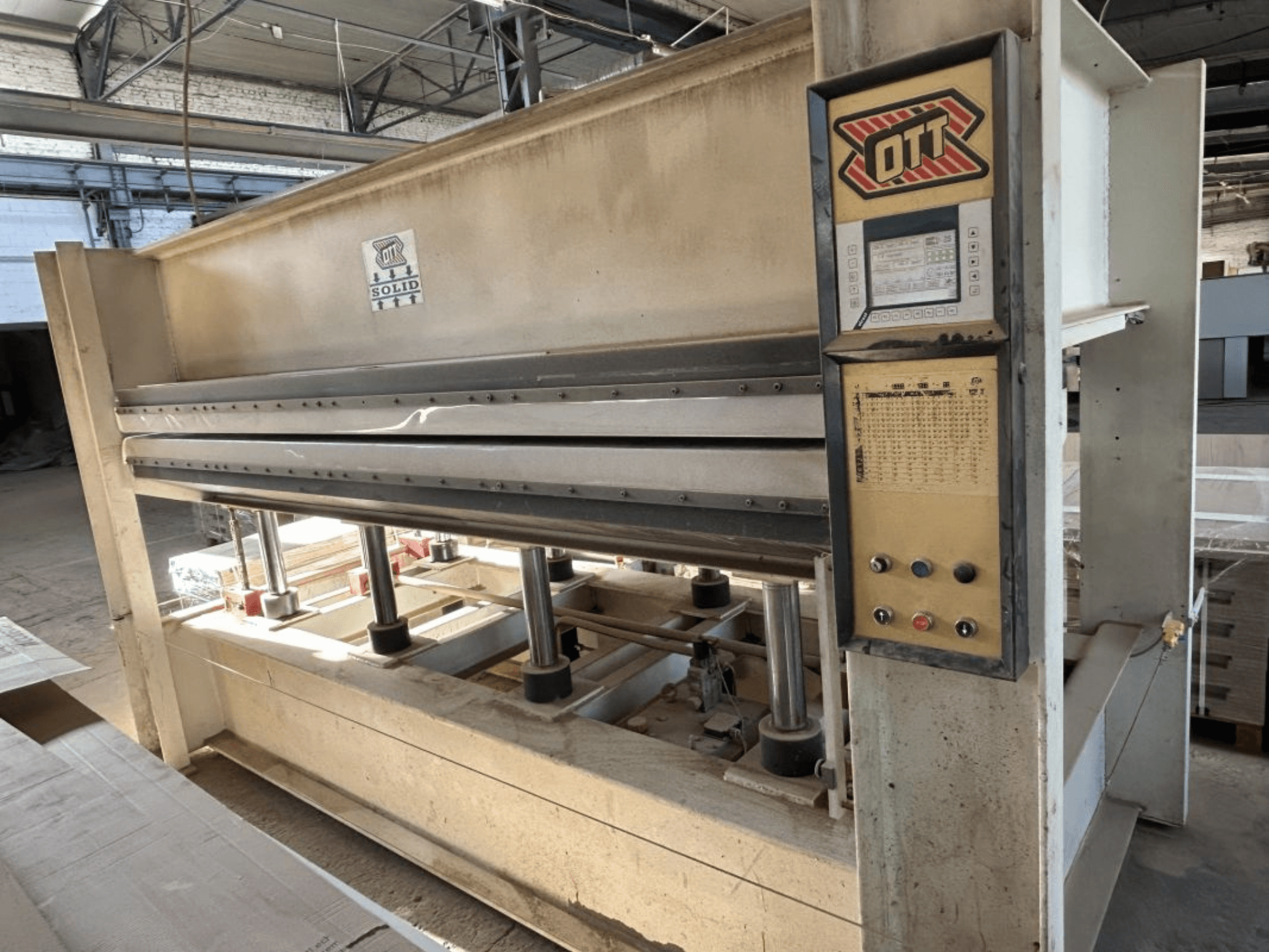 Framifrån sett på lamineringspressen OTT SOLID 16-32, med kontrollpanelen och de hydrauliska komponenterna.