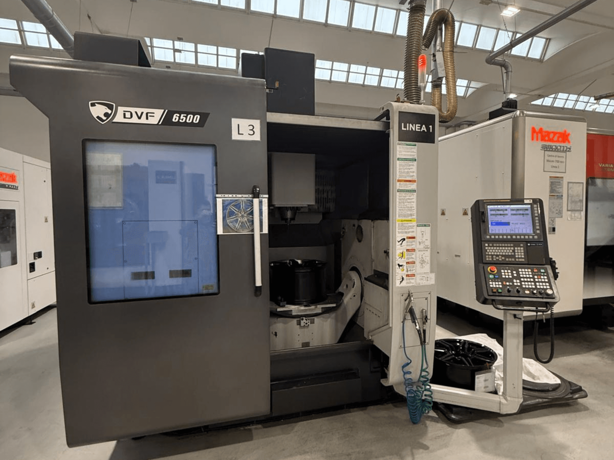 DVF 6500 CNC-maskin, framifrån, med kontrollpanel och inre utrymme med en fixtur för en del.