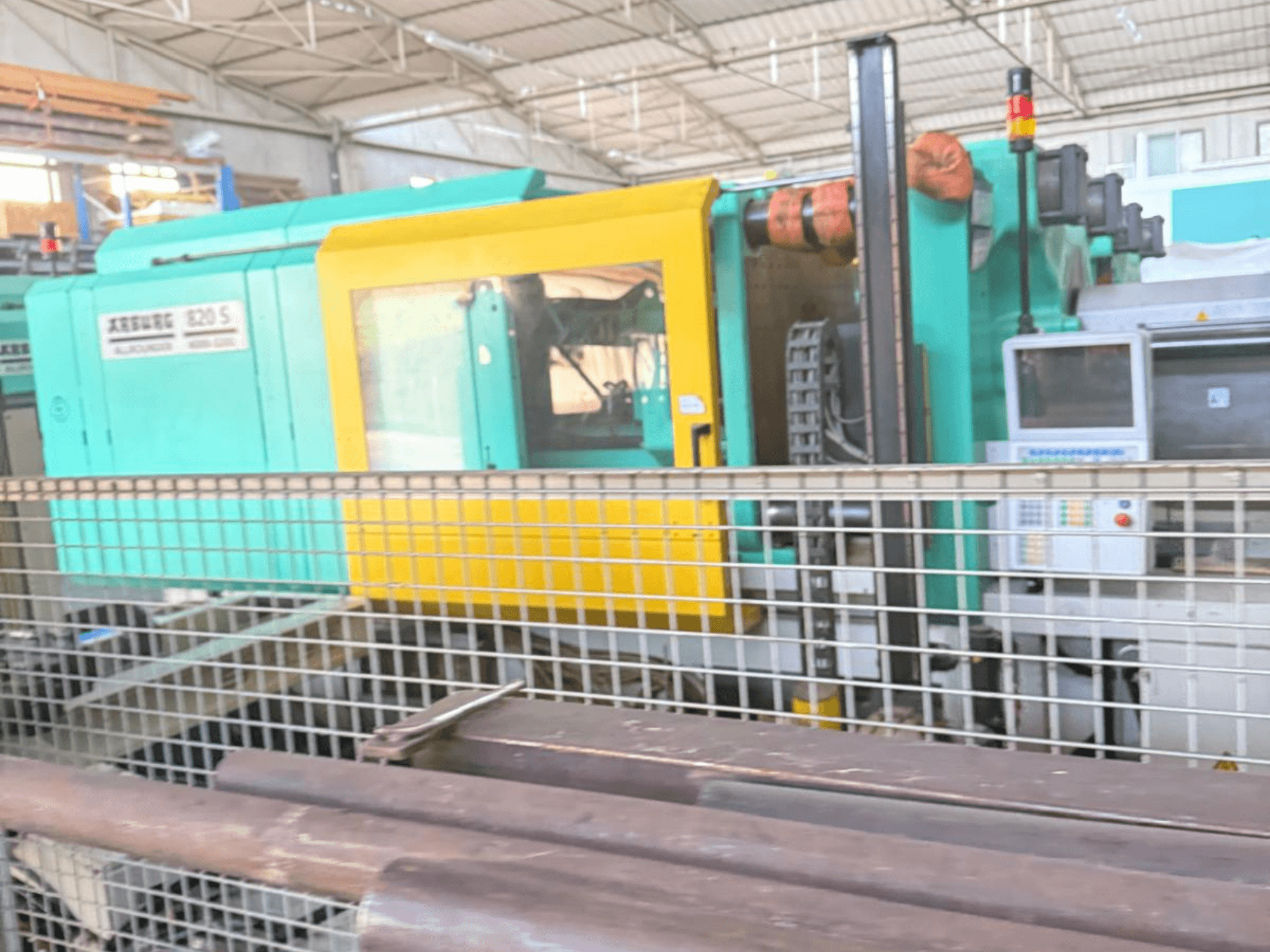 Hydraulisk formsprutningsmaskin Arburg SELECTA 820 S 4000-3200, sidovy som visar kontrollpanelen och den livfulla designen i gult och blågrönt.