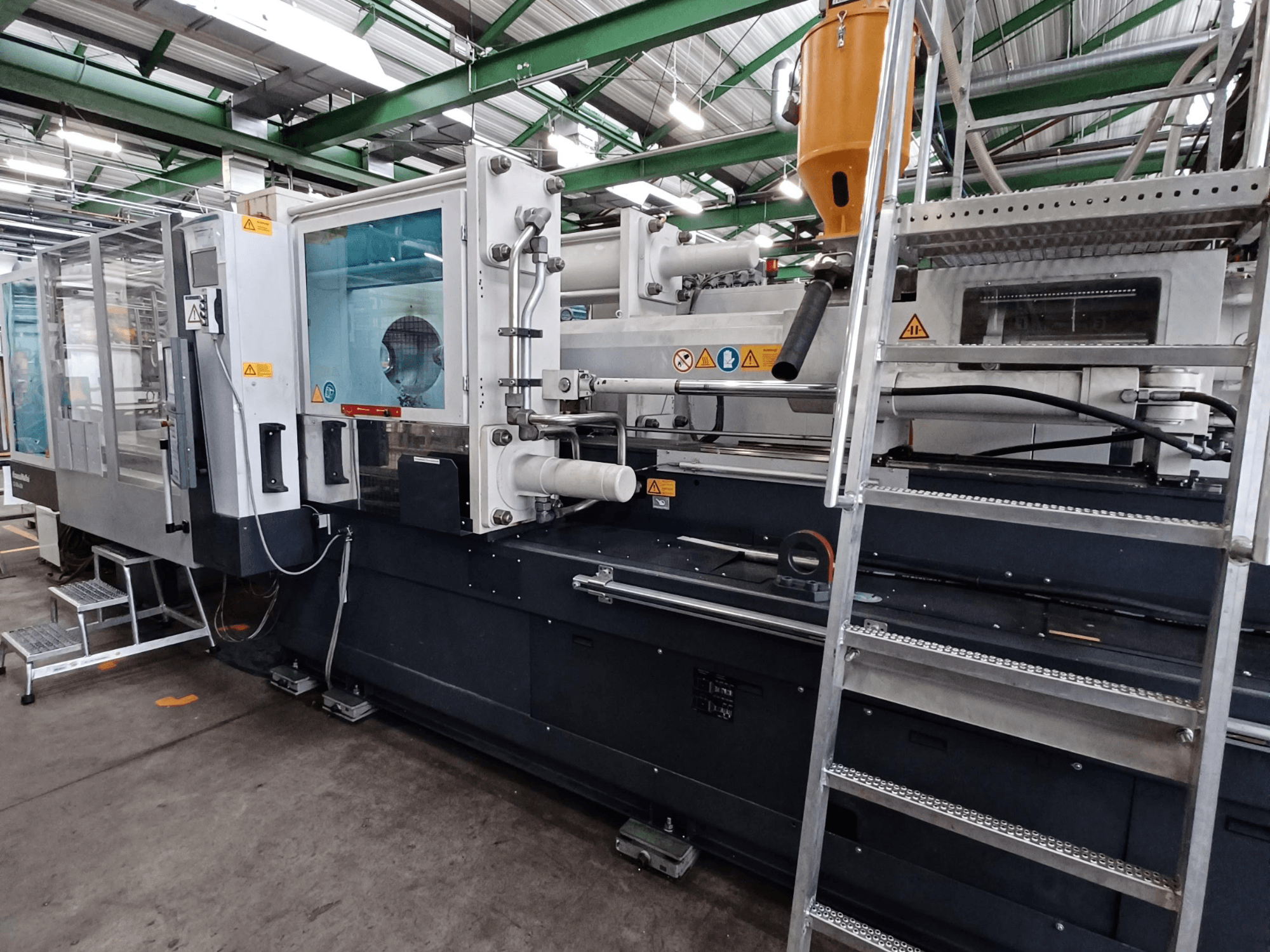 Industriell formsprutningsmaskin med en tydlig frontvy som visar varumärkesmärkning, kontrollpanel och materialbehållare.