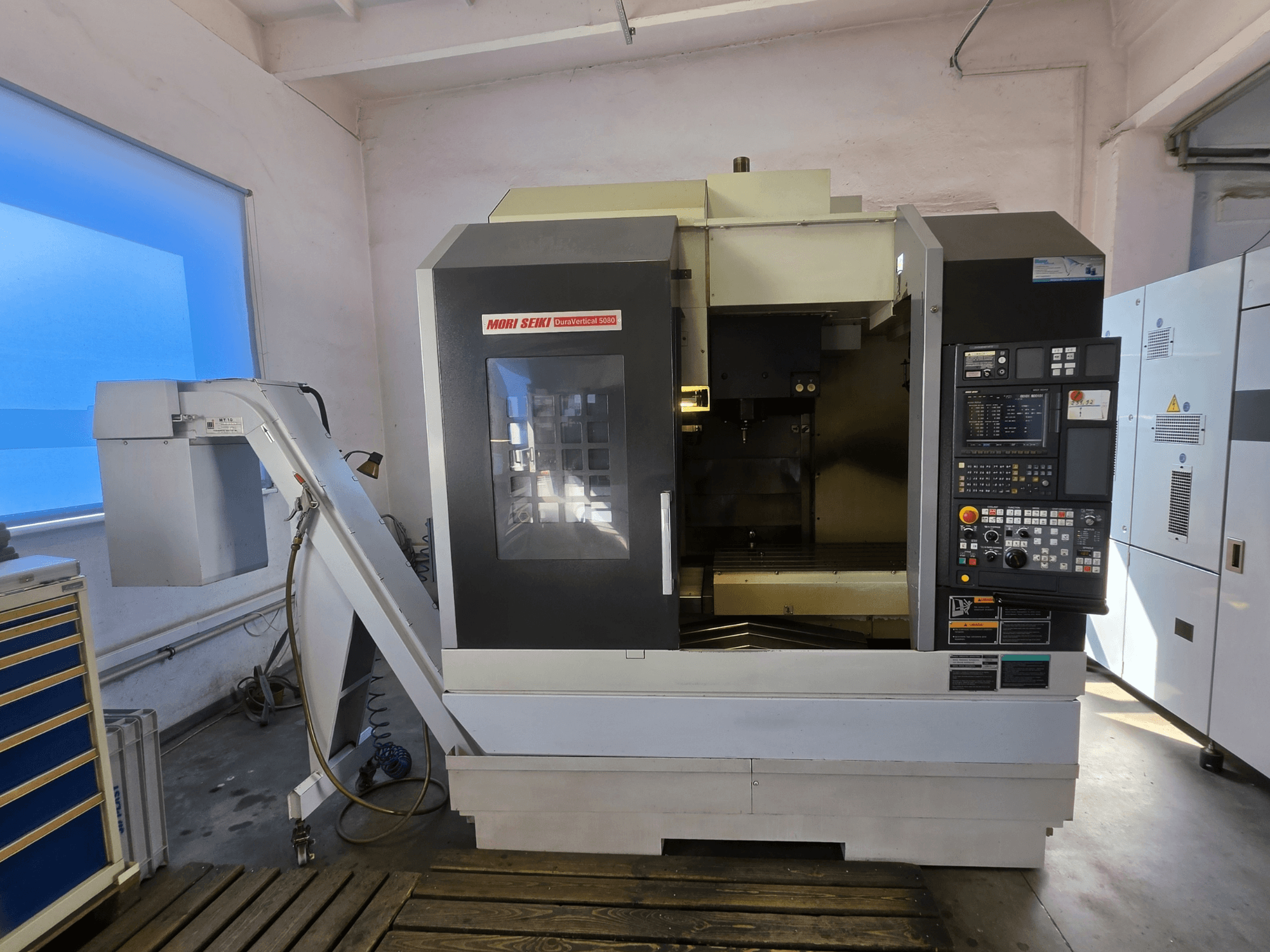 MORI SEIKI DuraVertical 5080 vertikalt bearbetningscenter, framifrån med kontrollpanelen, spindeln och verktygshållaren synliga.