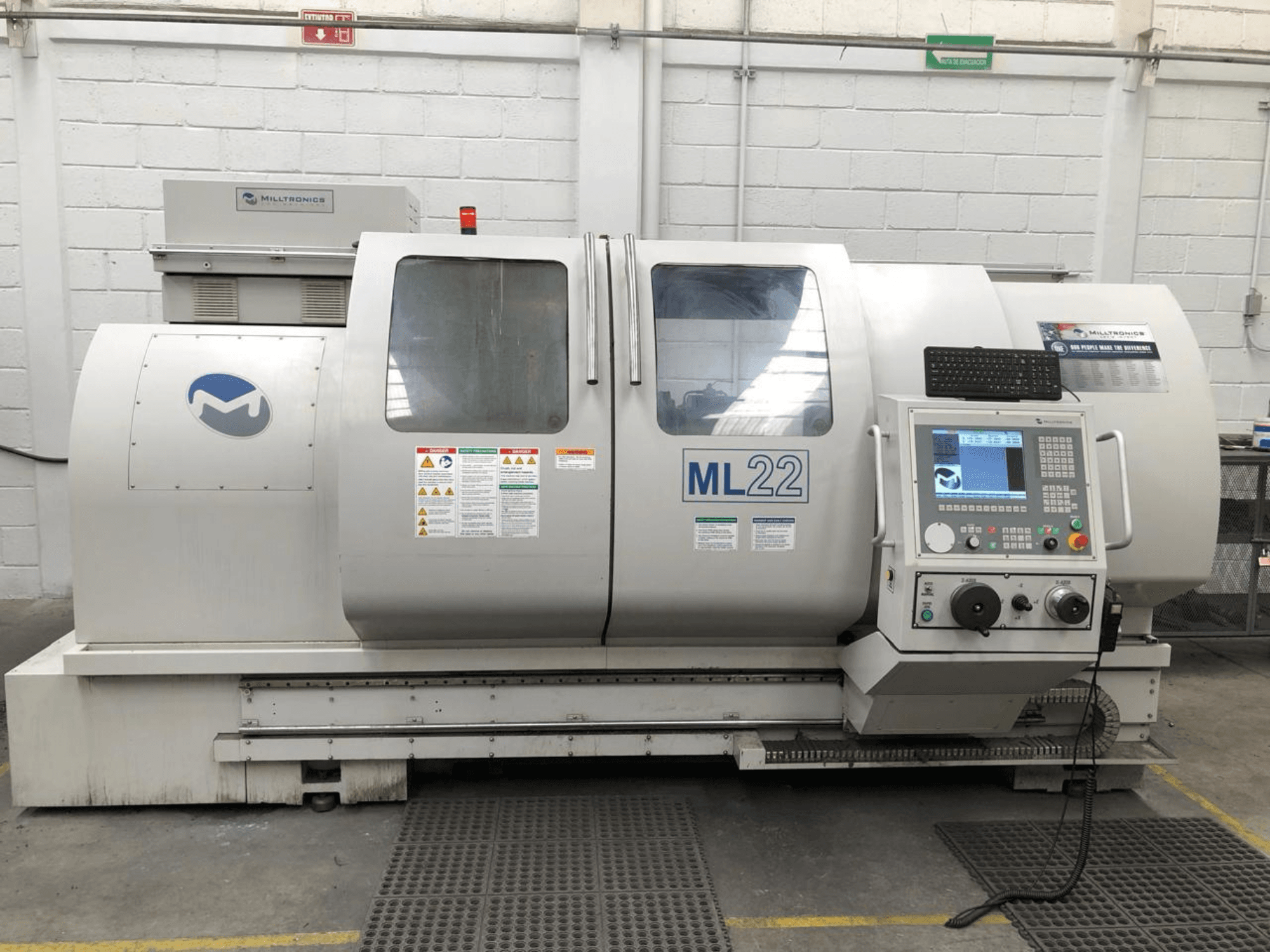 Vertikal fleroperationsmaskin MILLTRONICS RH 20, framifrån med kontrollpanel, märkeslogotyp och säkerhetsetiketter på maskinen.
