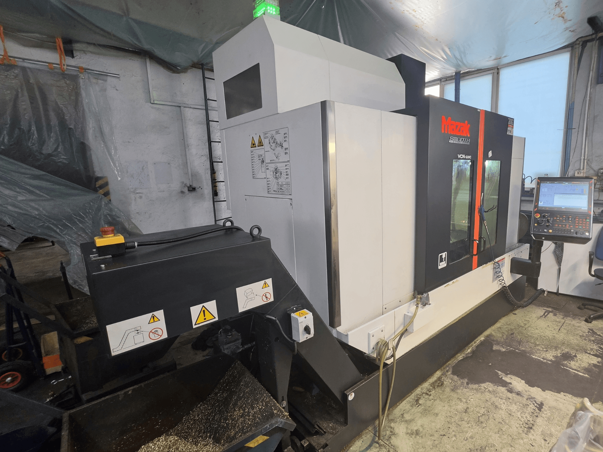 Mazak VCN-530C vertikalt bearbetningscenter, framifrån sett, med kontrollpanel, verktygskedja och driftsindikatorer.