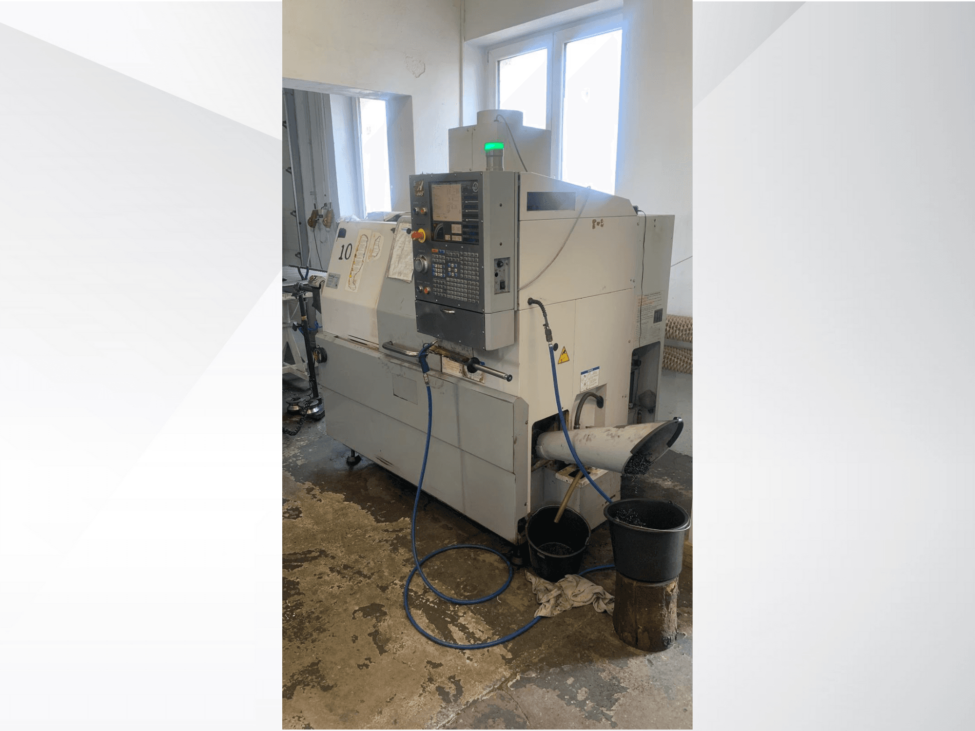 Haas CNC-maskinmodell med kontrollpanel, sidovy, med kylvätskeledning, avfallsrännor och förvaringsbehållare nedanför.