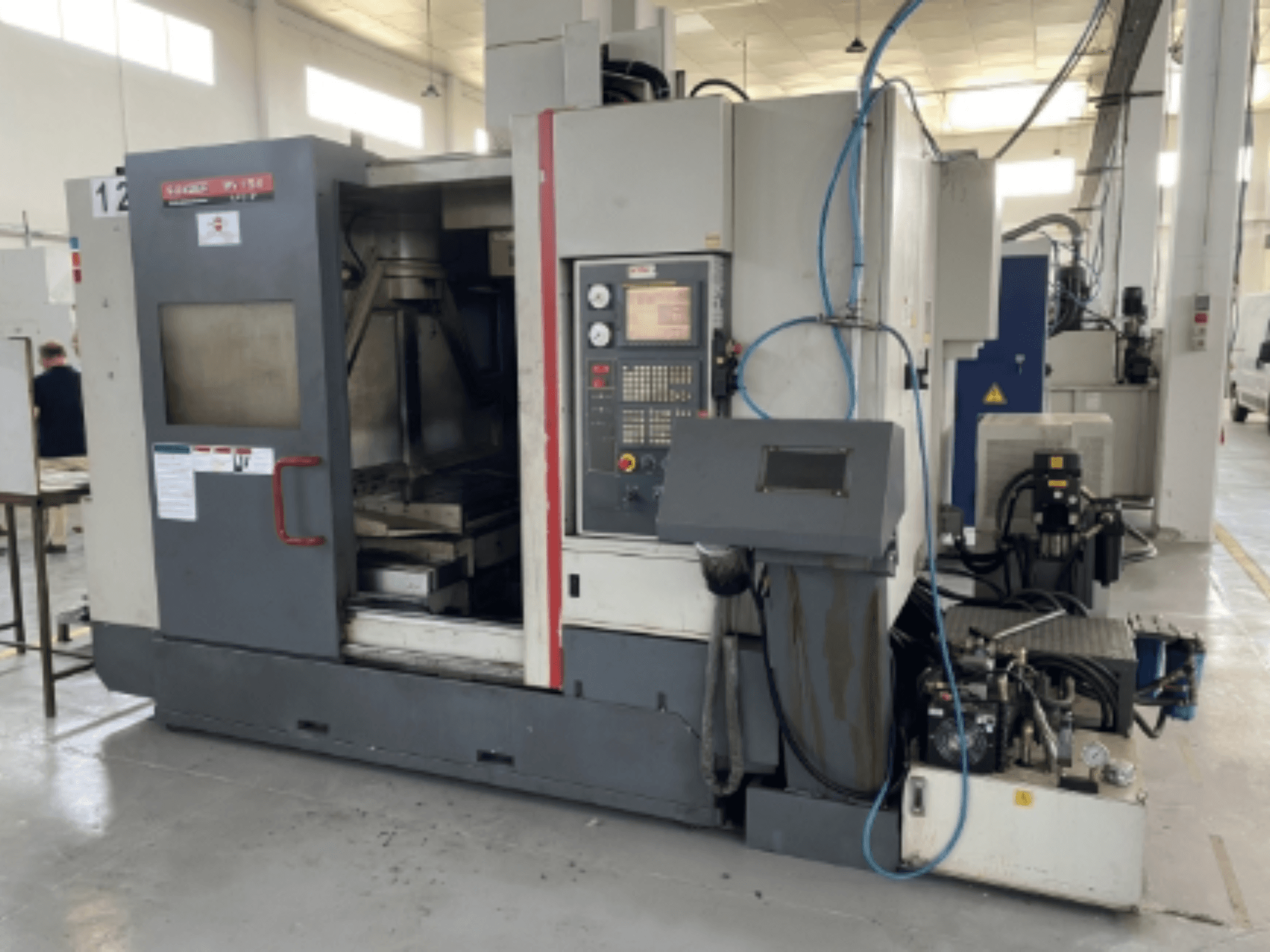 Quaser MV154APC-912 vertikalt bearbetningscenter, framifrån med kontrollpanel, öppen dörr och maskinkomponenter.