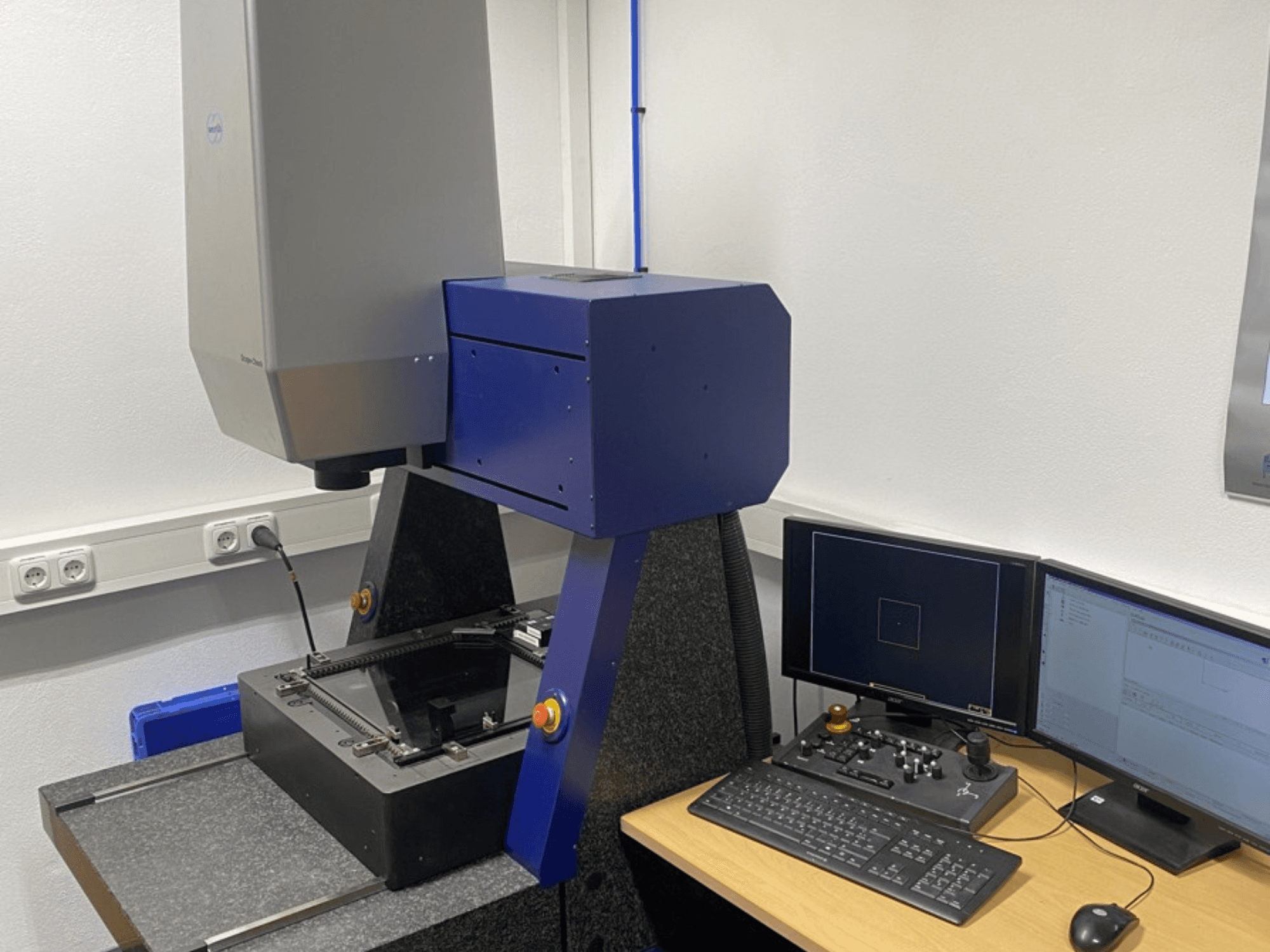 Werth Scope-Check 400 CMM i ett labb, visar mäthuvudet och kontrollpanelen med skärmar och tangentbord.