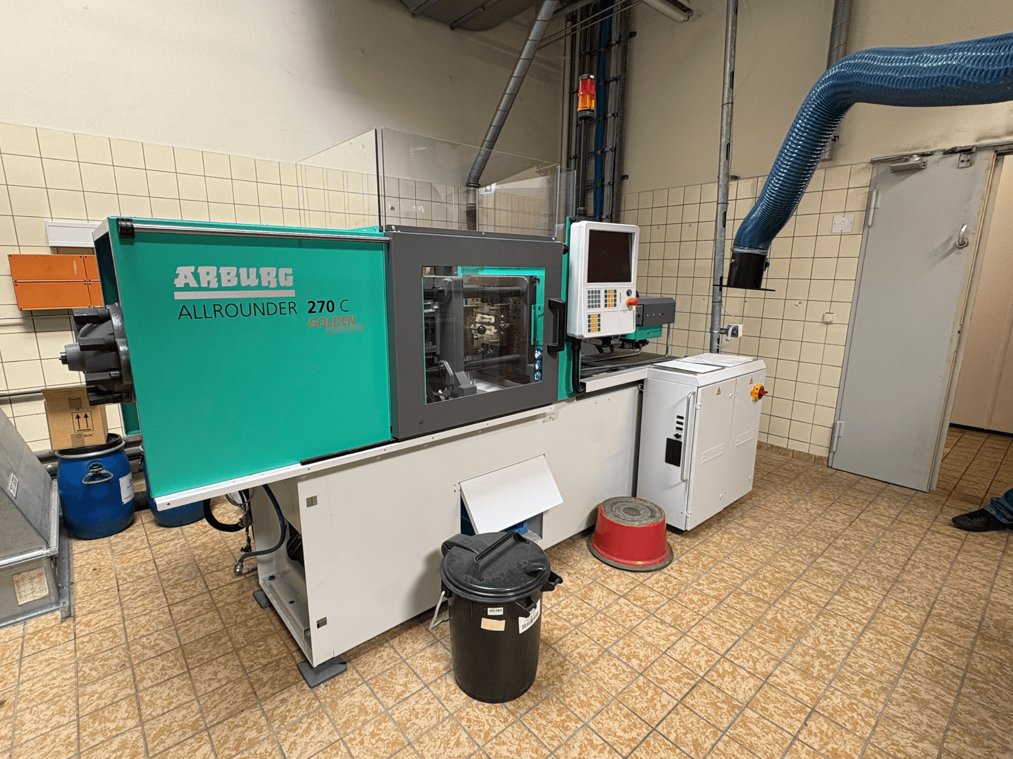 Hydraulisk formsprutningsmaskin Arburg ALLROUNDER 270 C sett från sidan, med manöverpanel och anslutna enheter.