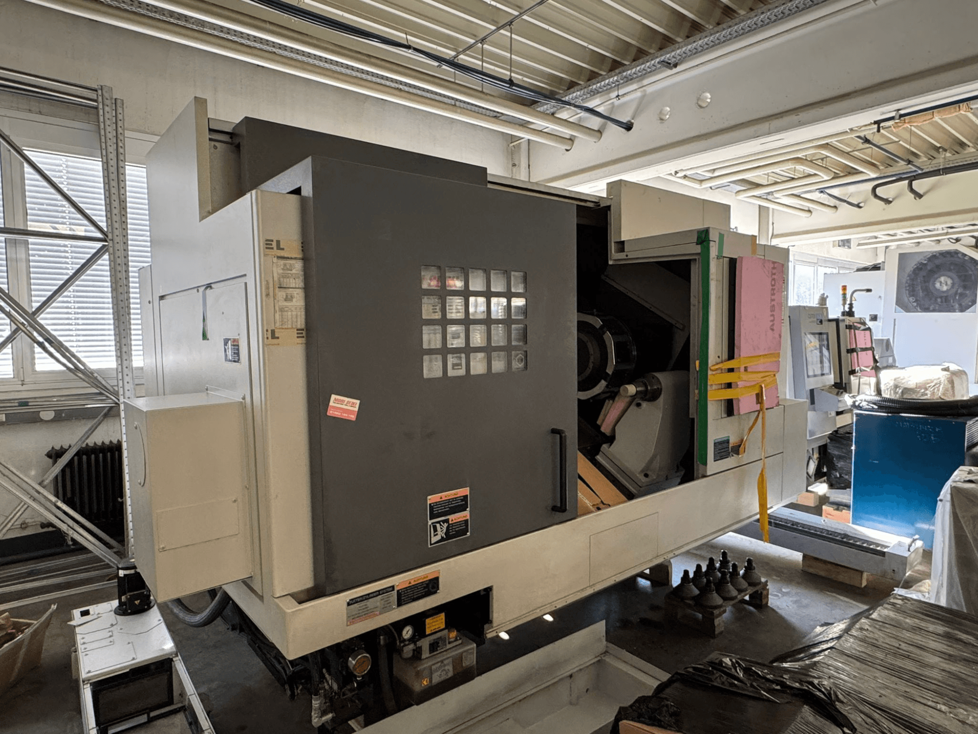 MORI SEIKI NL 3000 MC/700 horisontell svarv, framifrån sett med kontrollpanel, förvaringsutrymme och skyddsöverdrag.