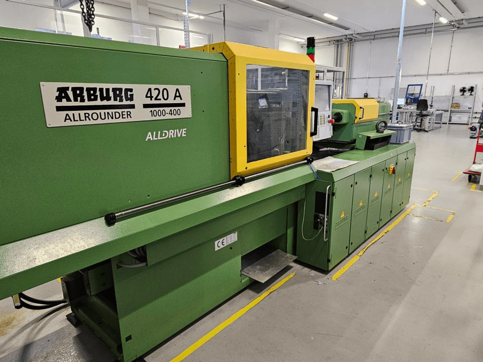 ARBURG 420 A Allrounder 1000-400, framifrån; grön maskin med gul panel, pekskärm och säkerhetsanordningar.