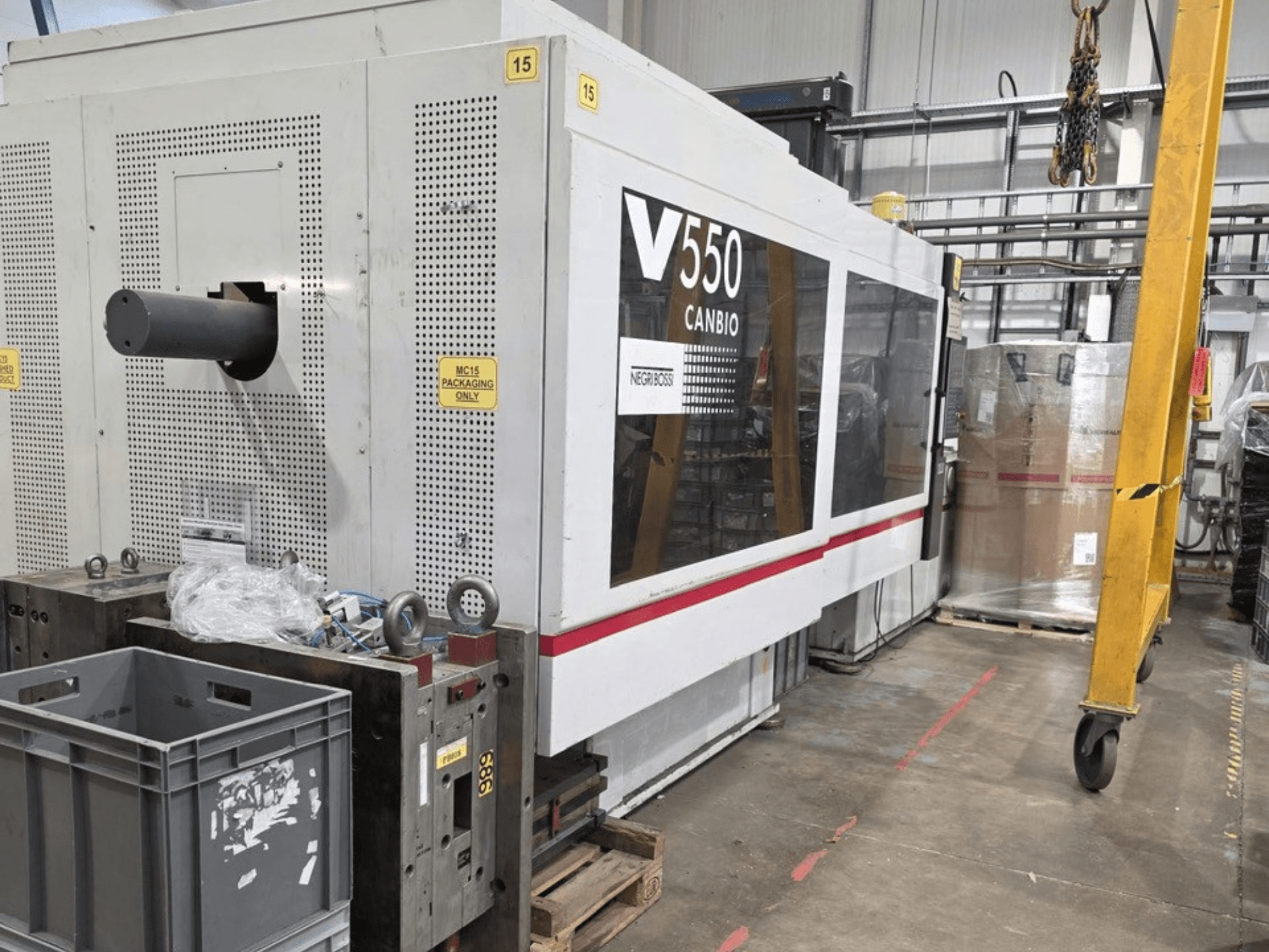 Negri Bossi V55000H-4250 hydraulisk formsprutningsmaskin, sidovy, med kontrollpanel och grå lådor i förgrunden.