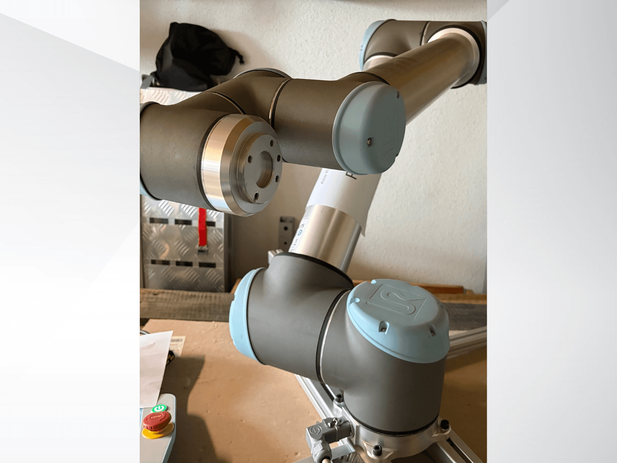 Närbild från sidan av en UR10-robotarm från Universal Robots, med leder och gråblå designelement markerade.