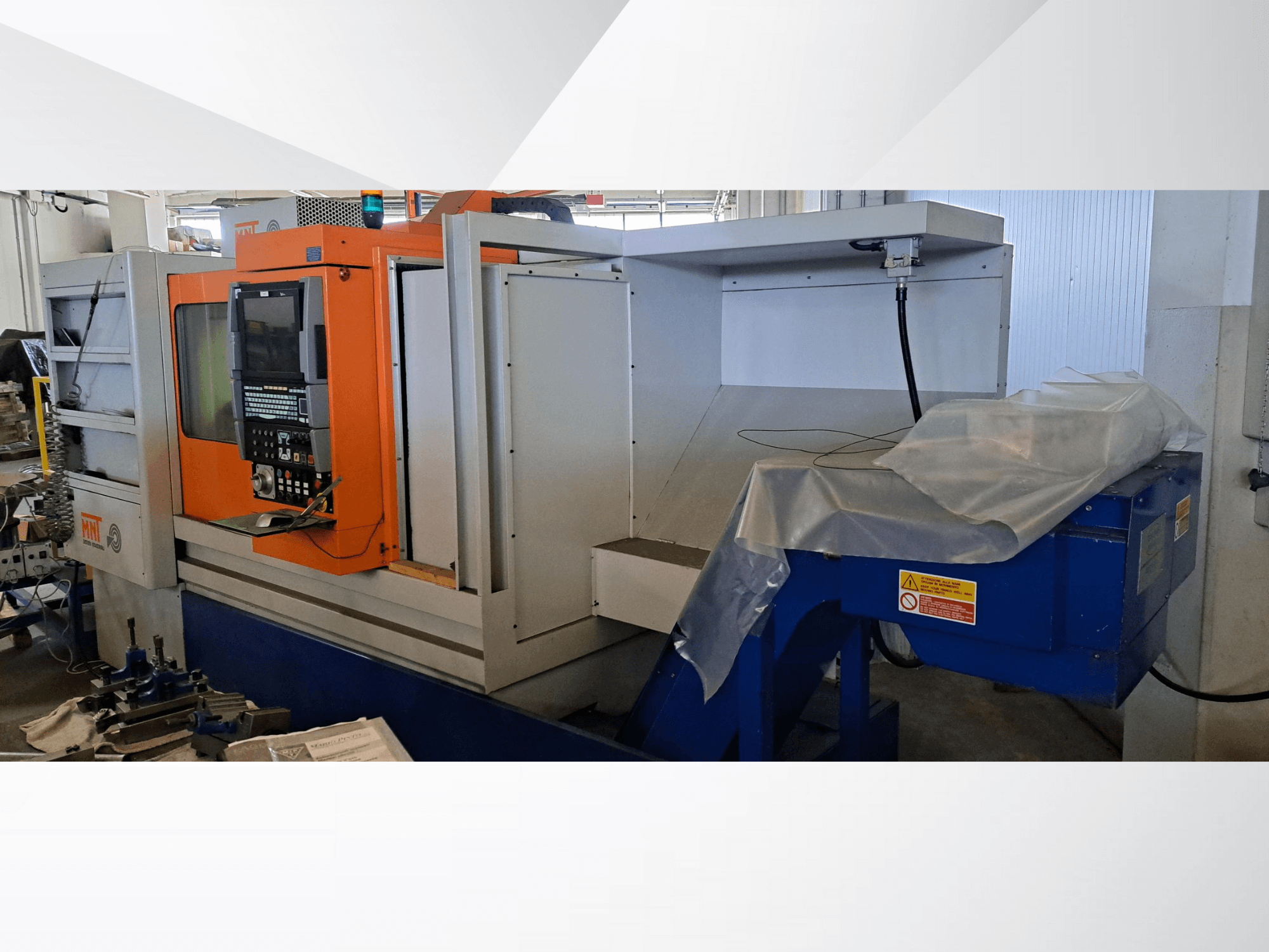 MNT CNC-maskin, framifrån, med orange kontrollpanel, stort bearbetningsområde och blå spånhanteringsenhet.
