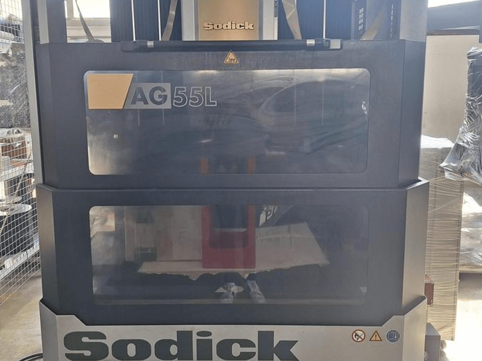 Sodick AG 55L Die-Sinking EDM Machine, framifrån med reglage synliga genom genomskinliga paneler, som visar arbetsutrymmet inuti.