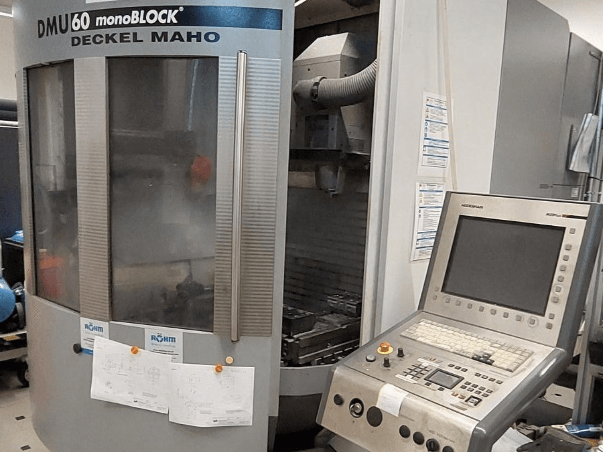 DMU 60 monoBLOCK av Deckel Maho, frontvy av en CNC-fräsmaskin med en kontrollpanel och tekniska ritningar bifogade.