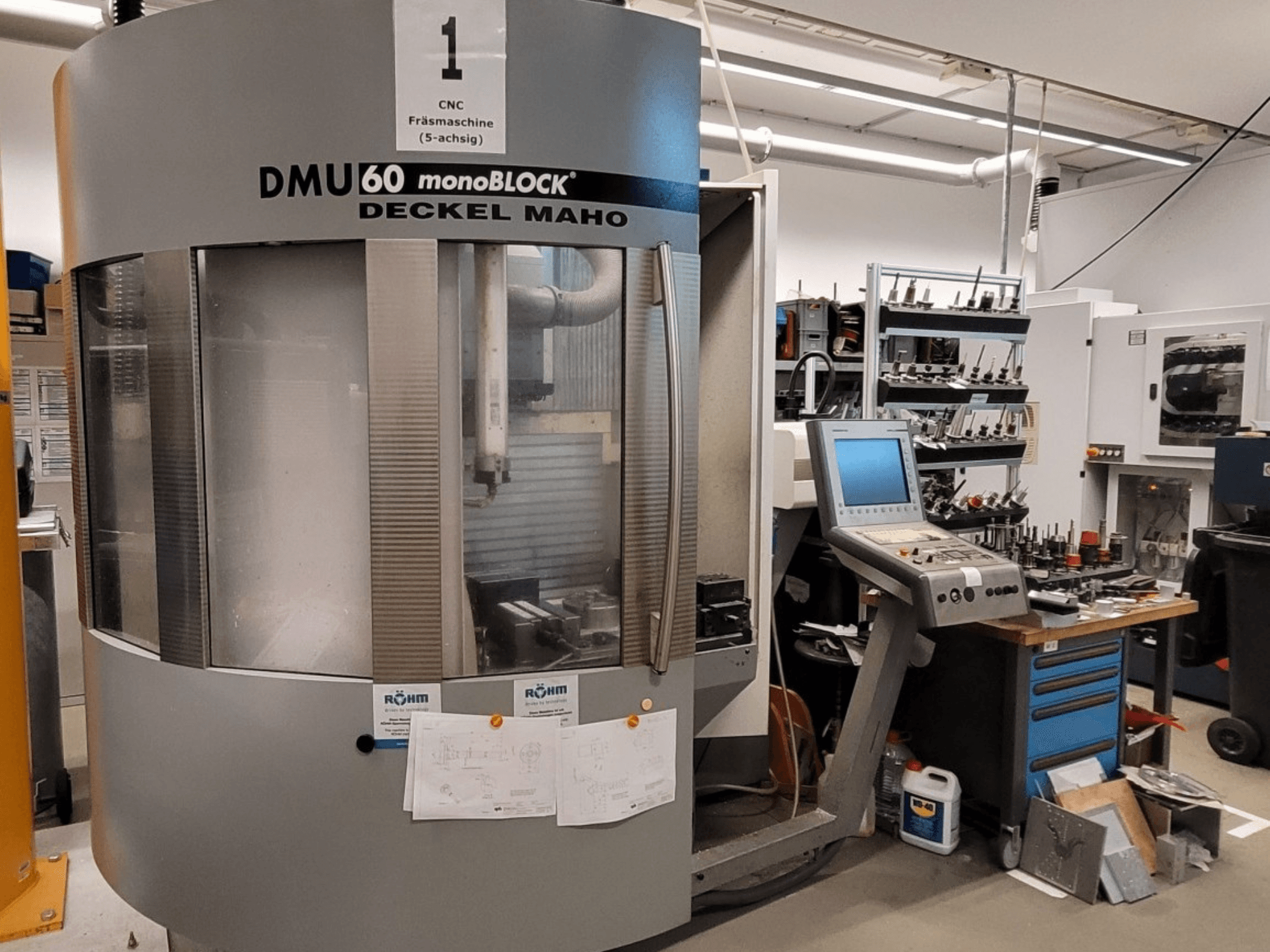 CNC-fräsmaskin DECKEL MAHO DMU 60 monoBLOCK framifrån, med kontrollpanel och verktygsförvaring bredvid.